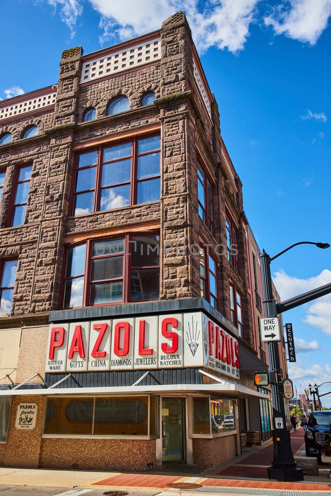 Vintage corner jewelry store Pazols in downtown Muncie, Indiana featuring brownstone architecture and large windows under a clear daytime sky.