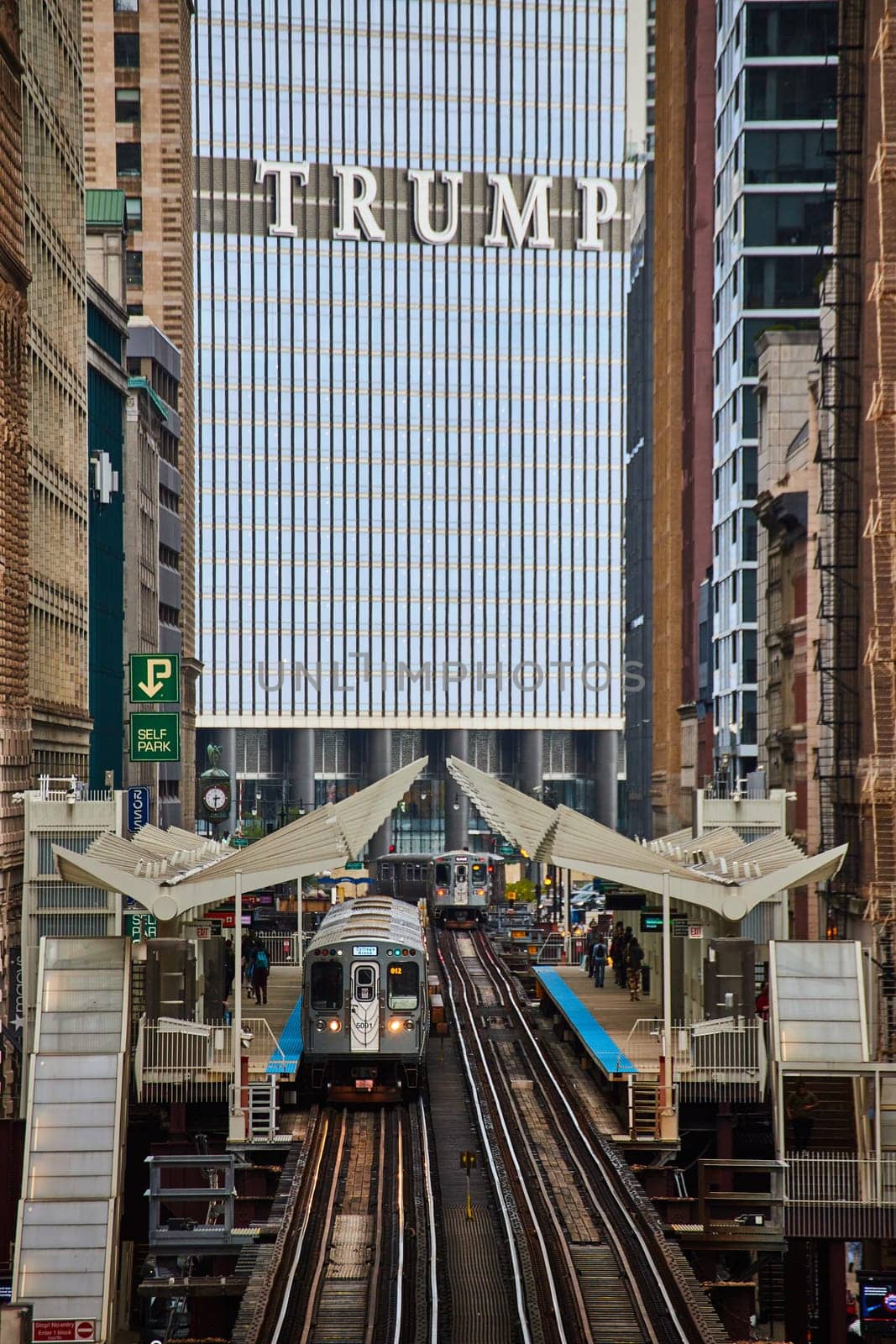 Bustling Chicago scene with trains, passengers at station, and dominant Trump Tower in bright daylight.