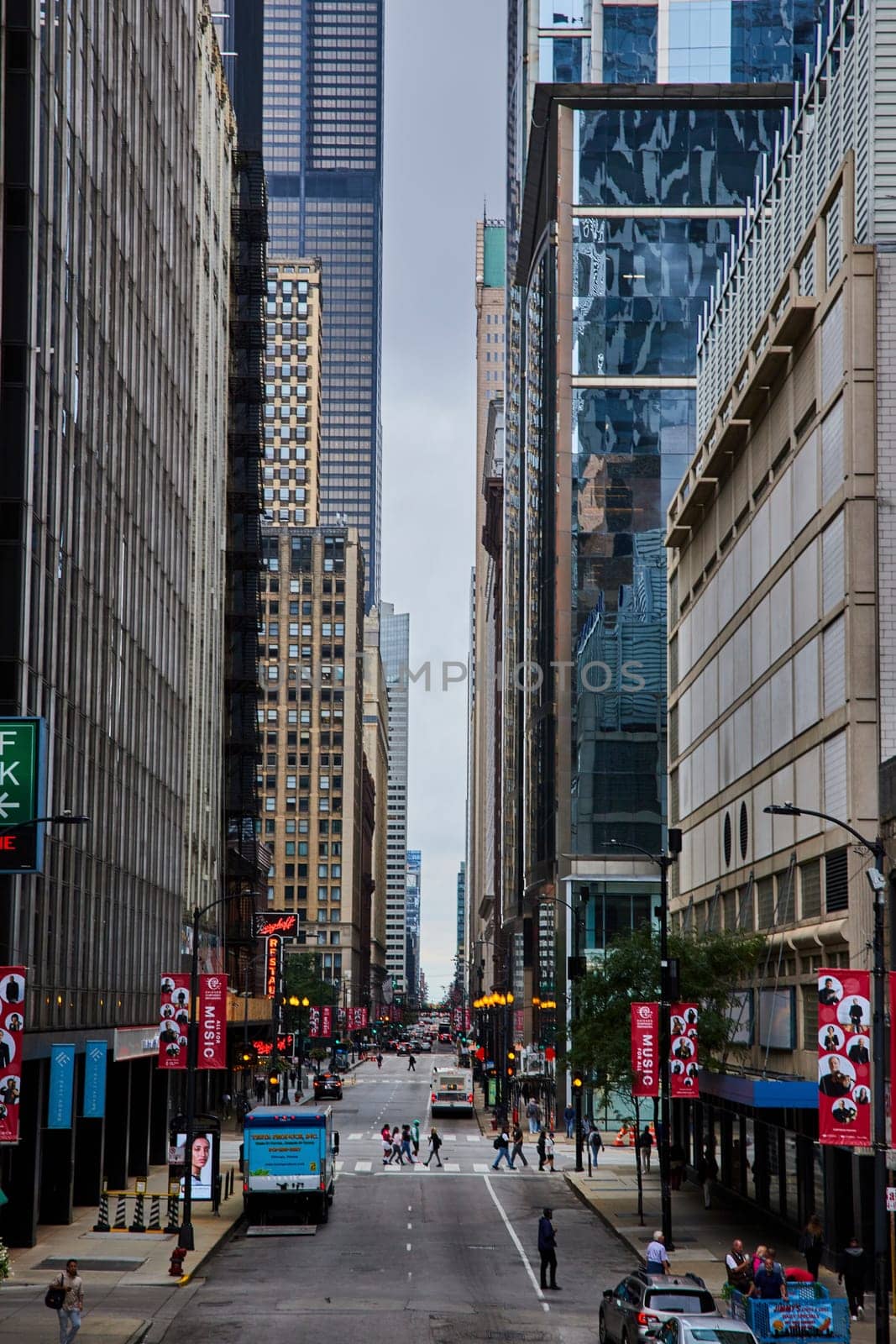 Image of Tourists and pedestrians on Chicago street corridor between skyscraper buildings on gloomy day