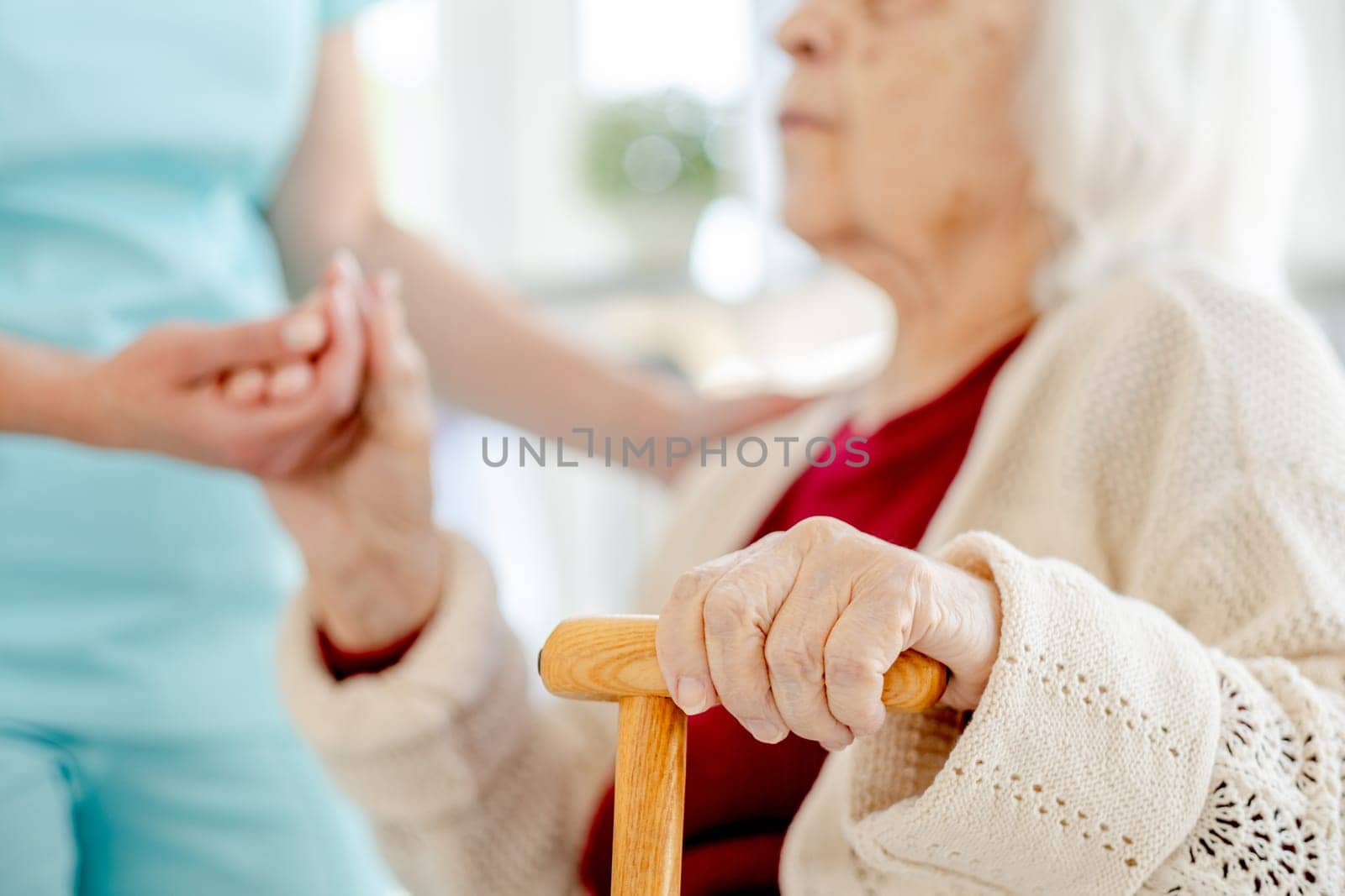 Close-Up Of Nurse'S Hand Holding Elderly Woman'S Hand With Cane by tan4ikk1