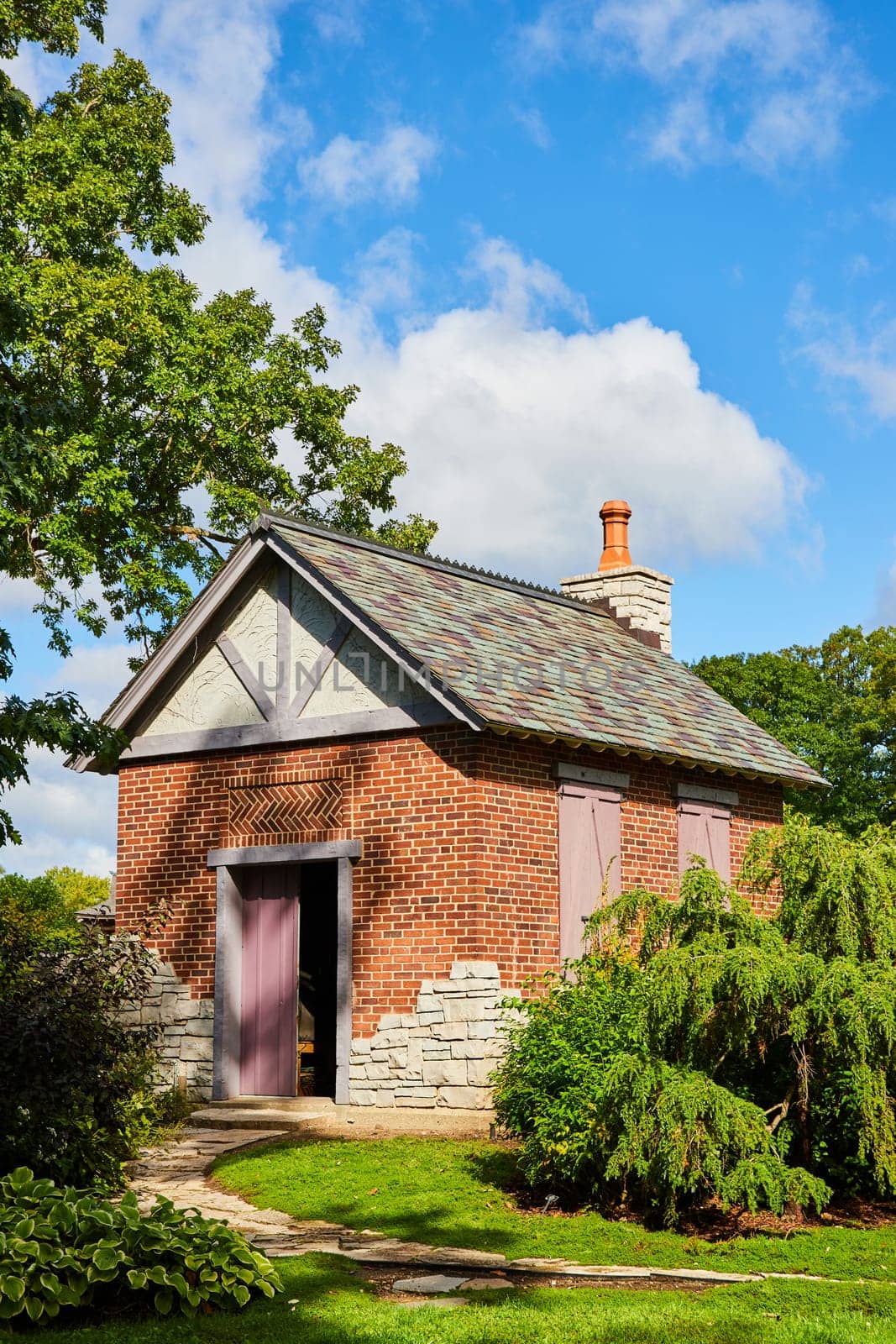 Charming red brick outbuilding with cream trim and terracotta chimney, set in lush Botanic Gardens, Elkhart, Indiana, 2023, perfect for heritage, architecture, and real estate themes.