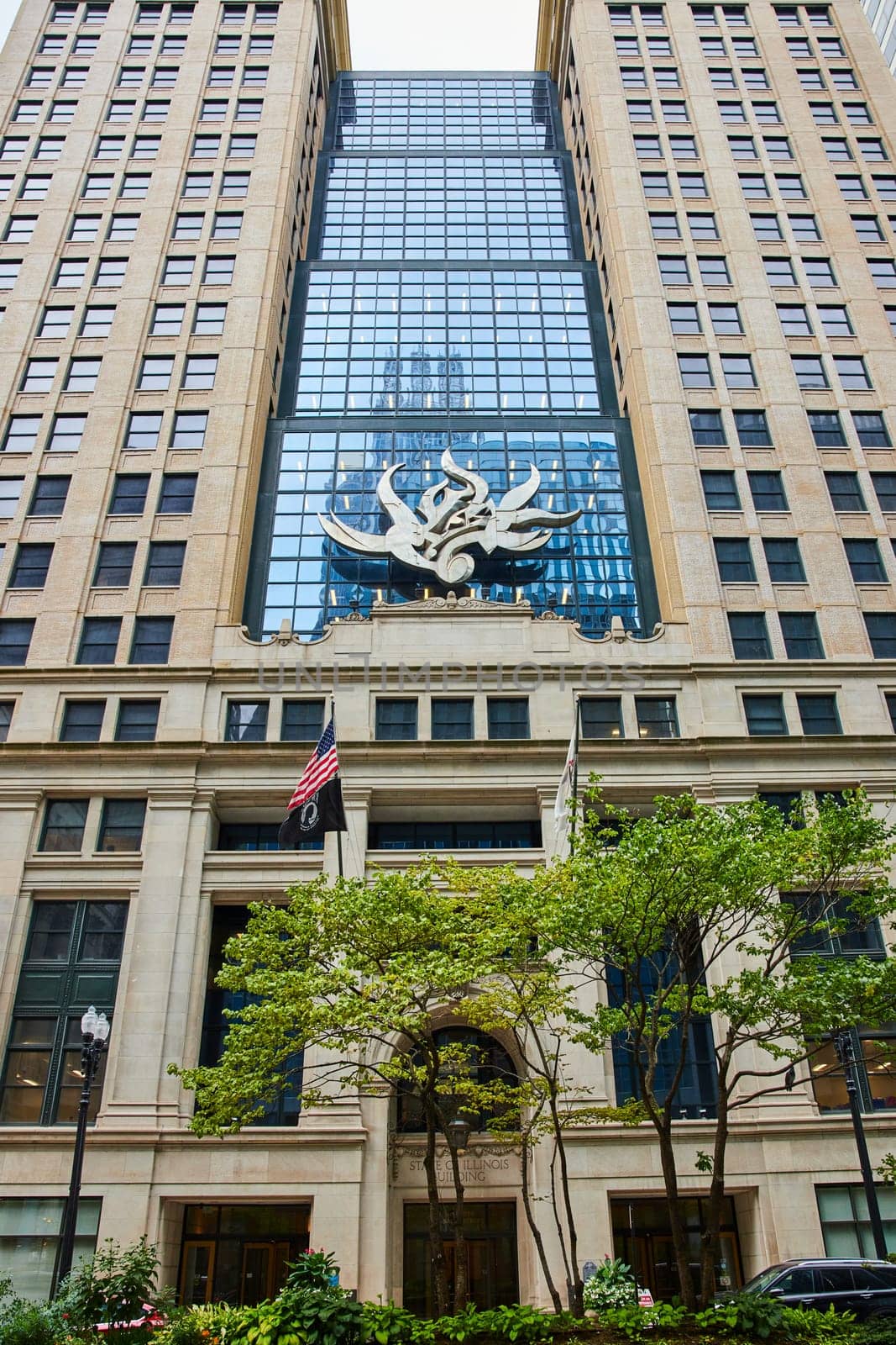 Chicago public art, abstract flame sculpture on building with reflective blue windows and green tree by njproductions