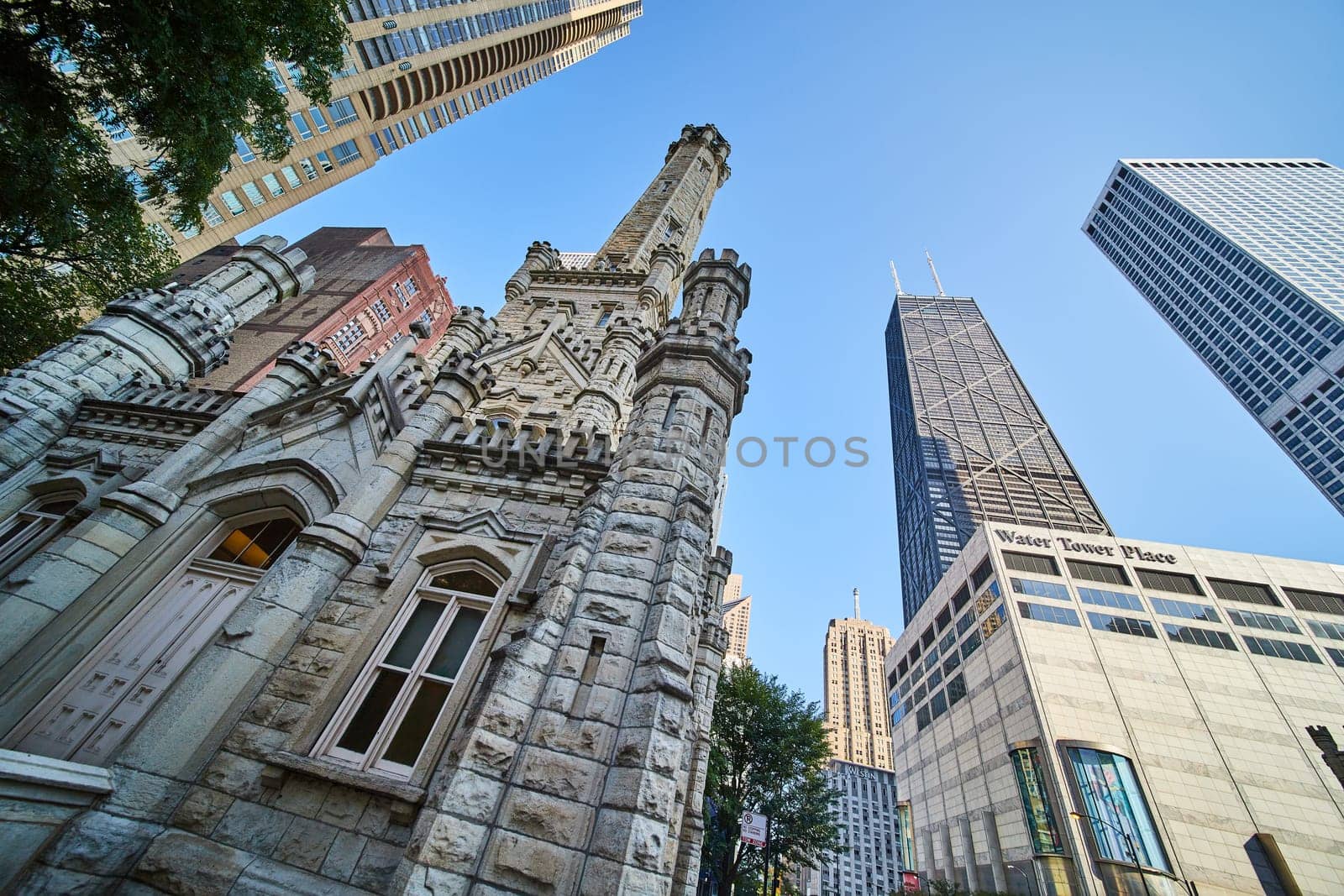 Image of Castle architecture of Chicago original, historic water tower under blue sky with city skyscrapers