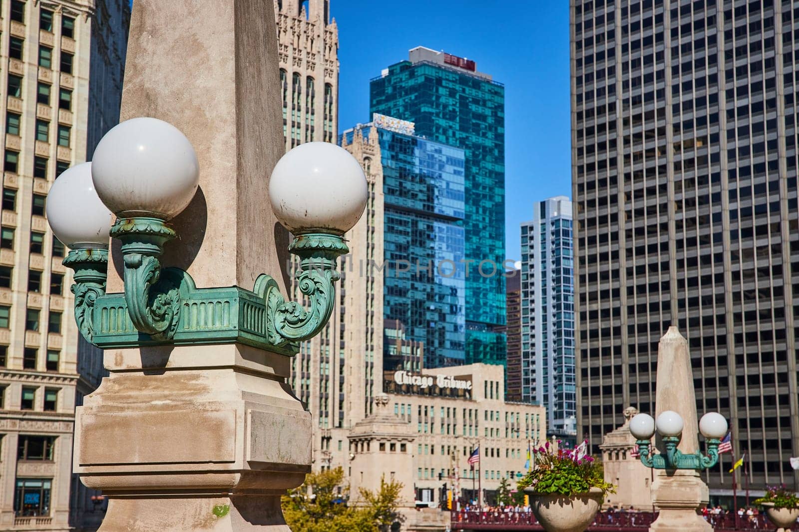 Image of Concrete pillar with three white globe lights on sunny summer day surrounded by Chicago skyscrapers