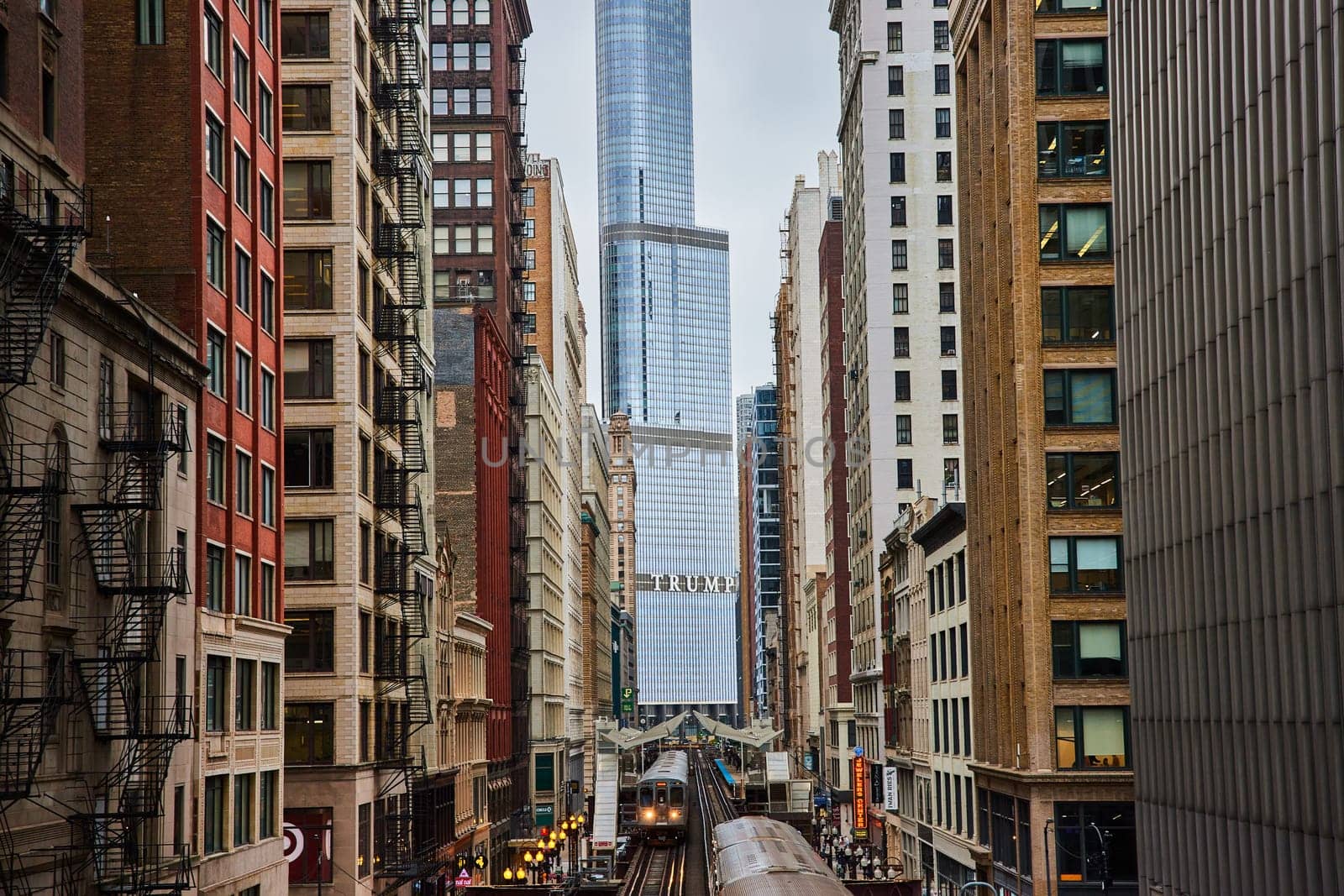 Elevated Train in Urban Canyon Amid Architectural Diversity by njproductions