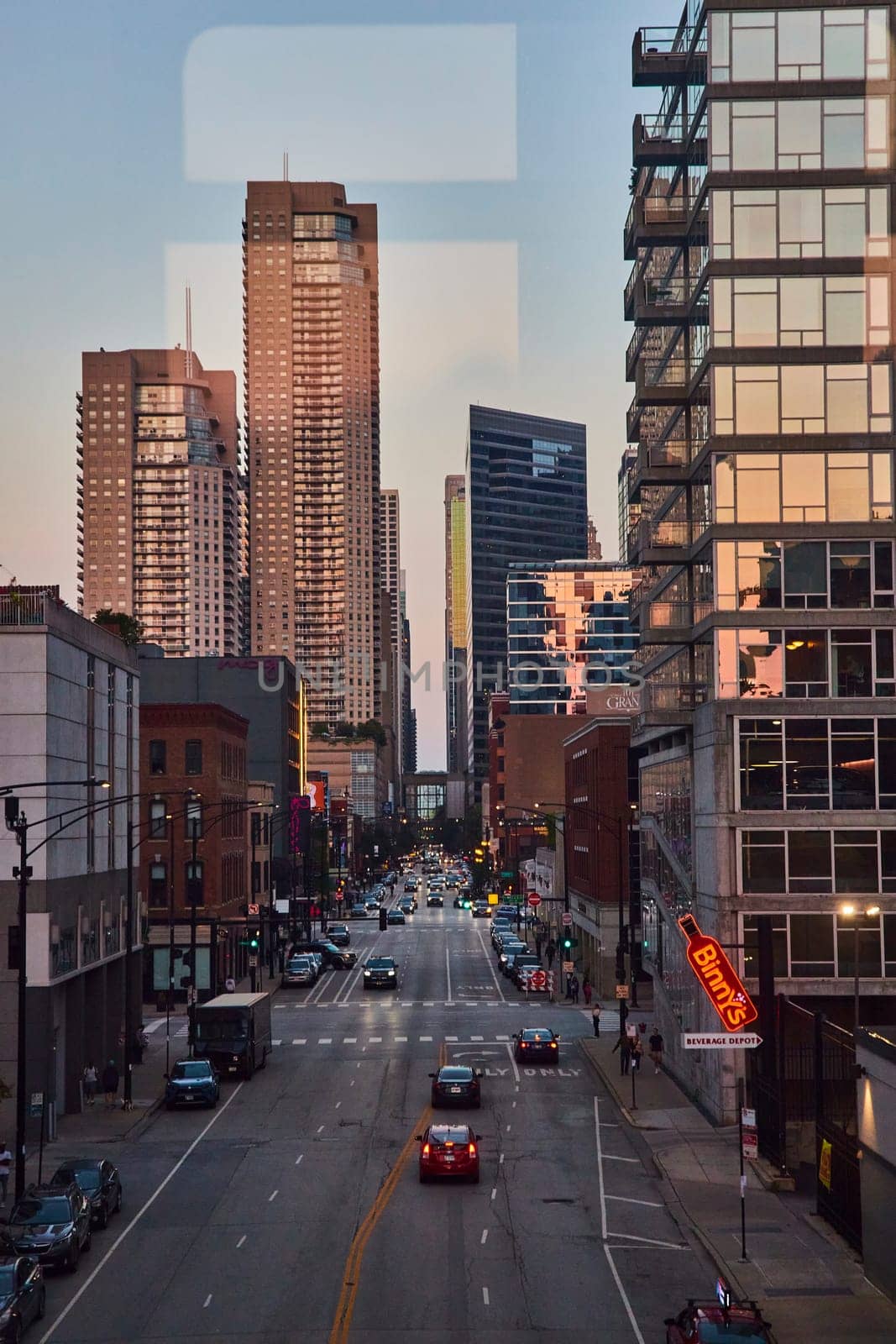 Image of Chicago skyscrapers with sunset lighting and blue sky over busy street, Illinois