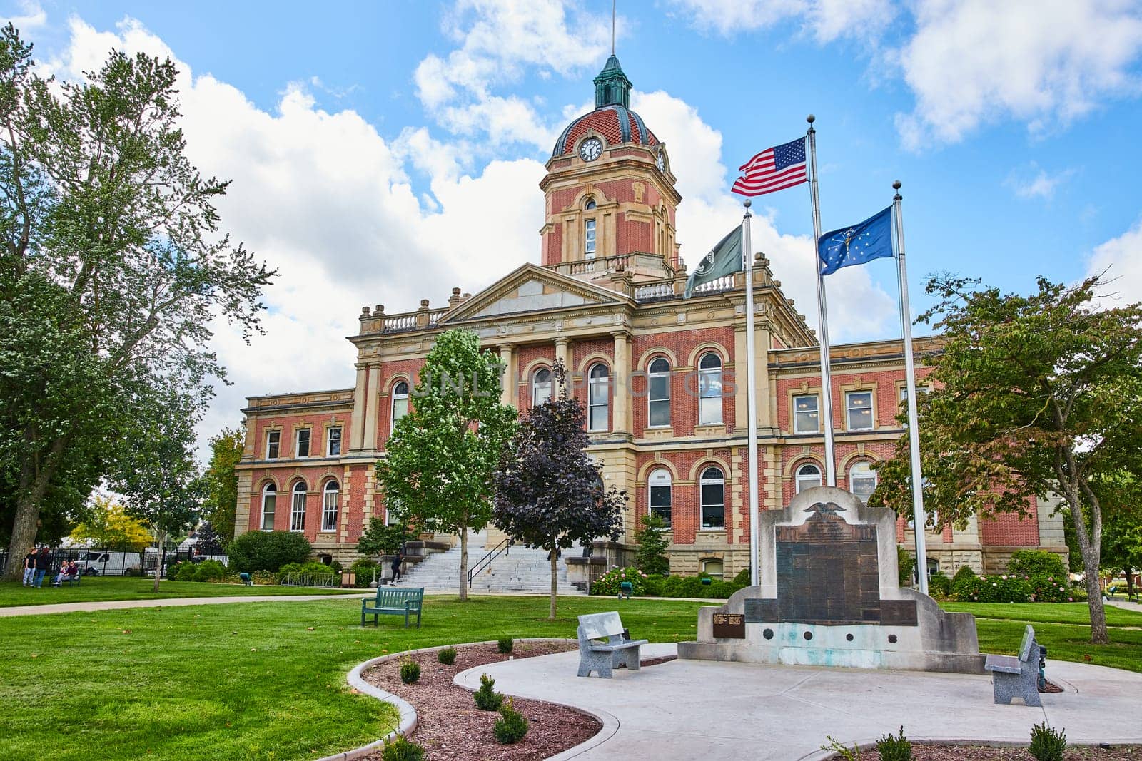 Elkhart County courthouse under cloudy blue sky and memorial with flags, law and order, Indiana by njproductions