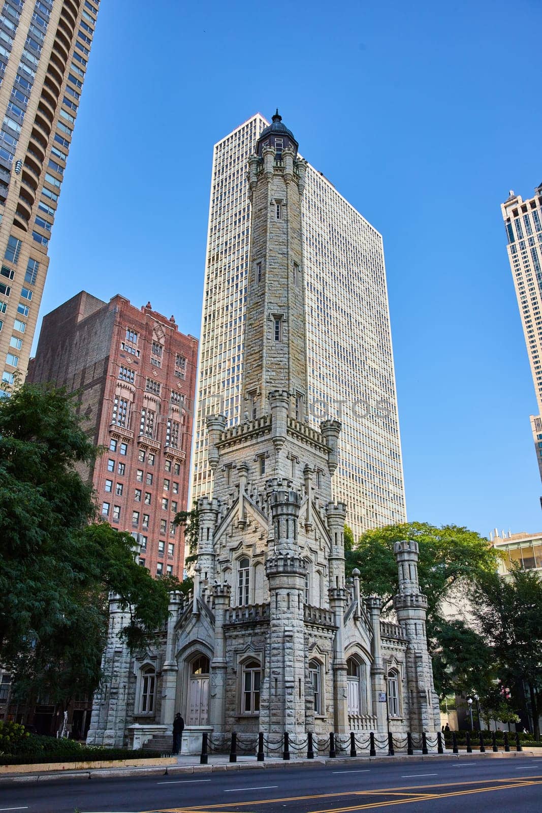 Image of Old, historic, original Chicago water tower with castle architecture under blue sky amid skyscrapers