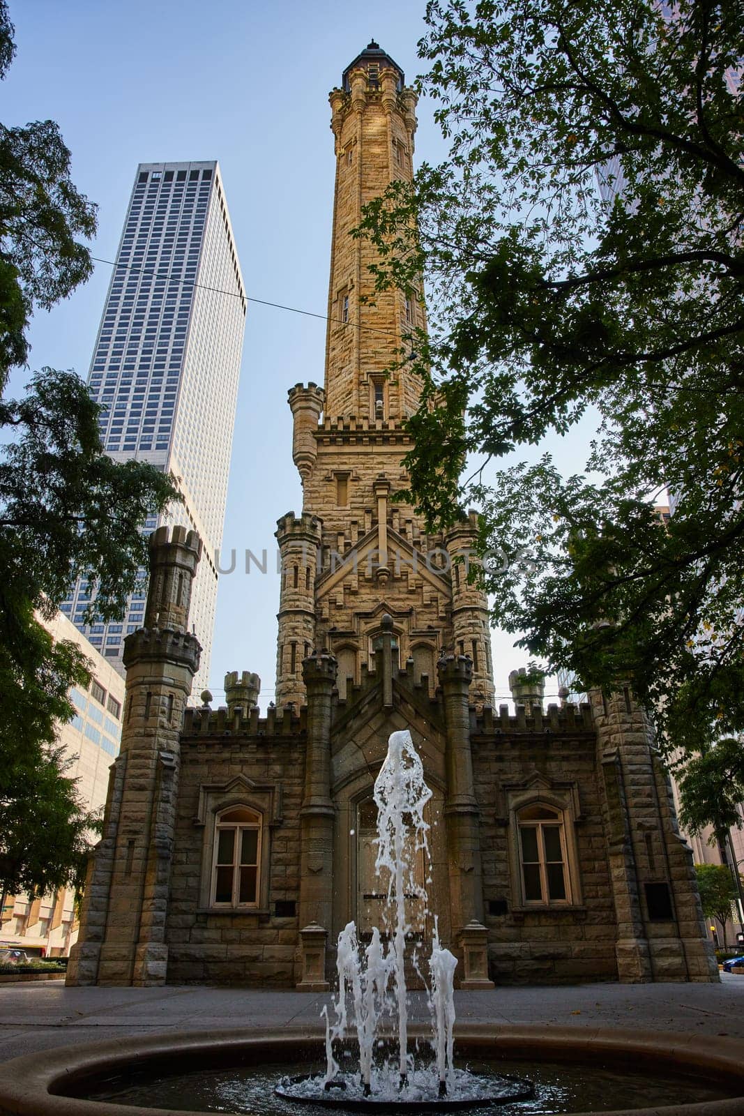 Image of Water fountain and trees in front of old Chicago water tower with historic architecture