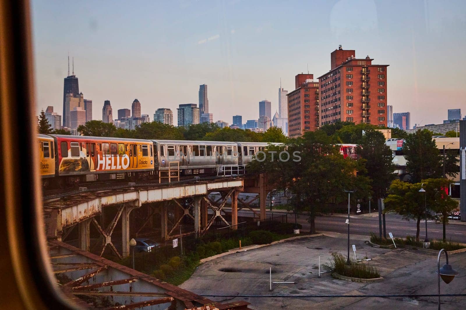 Train on raised track curving beside empty parking lot with Chicago skyscraper buildings in distance by njproductions