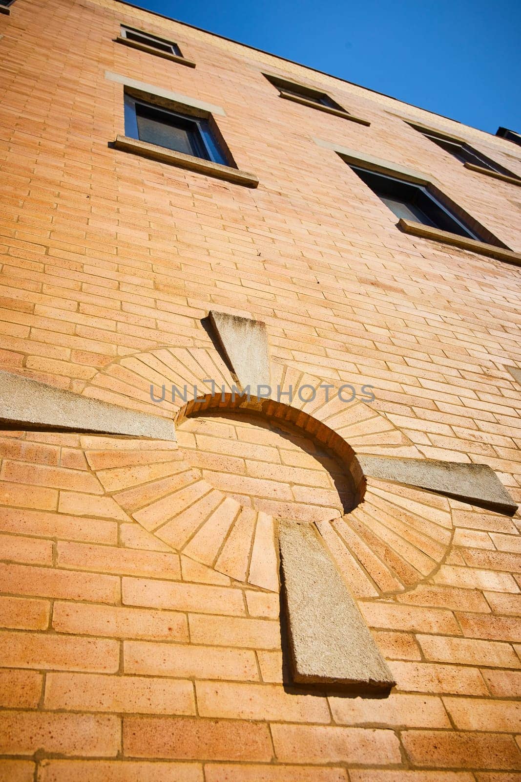 Image of Golden brick wall of building with upward view of windows and architecture design and blue sky