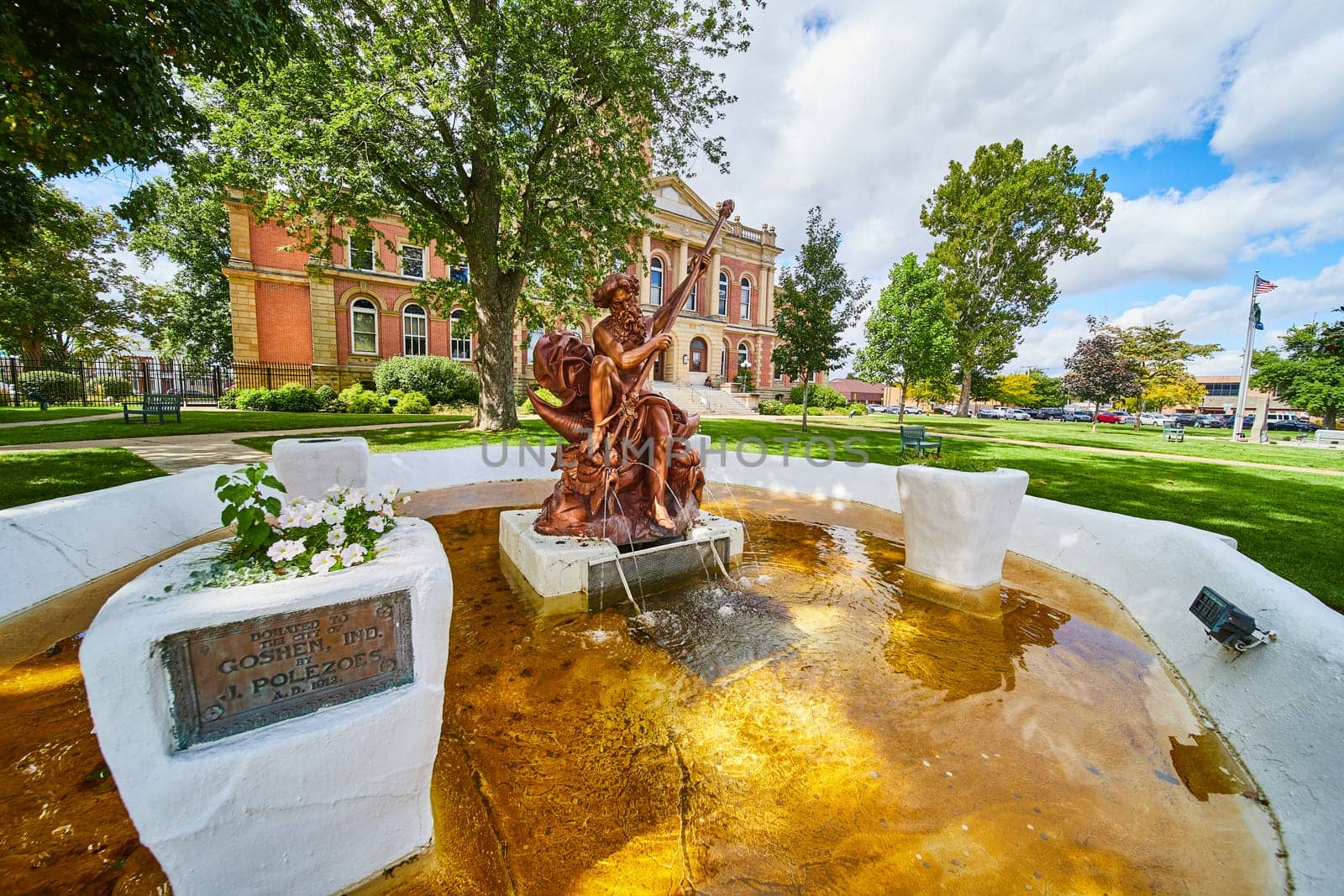 Poseidon bronze statue in golden yellow water fountain in front of Elkhart County courthouse, summer by njproductions