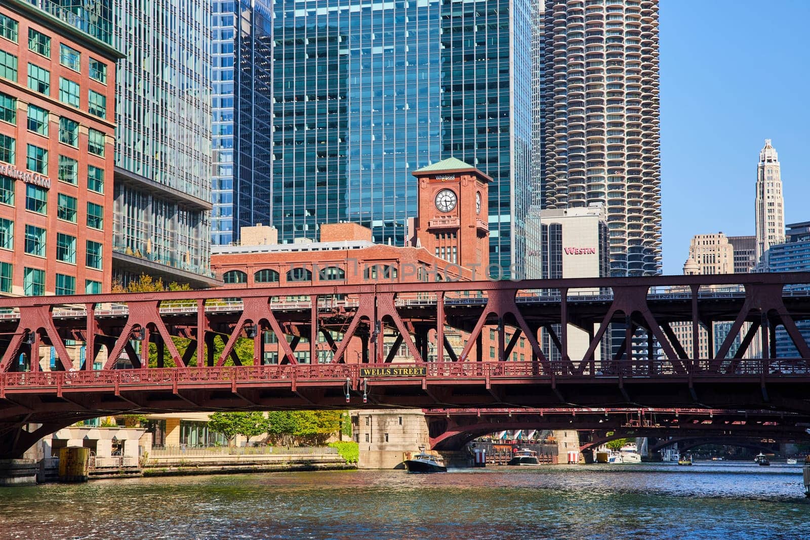 Image of Red iron bridge over Chicago canal with skyscrapers, hotels, and parking garage in summer