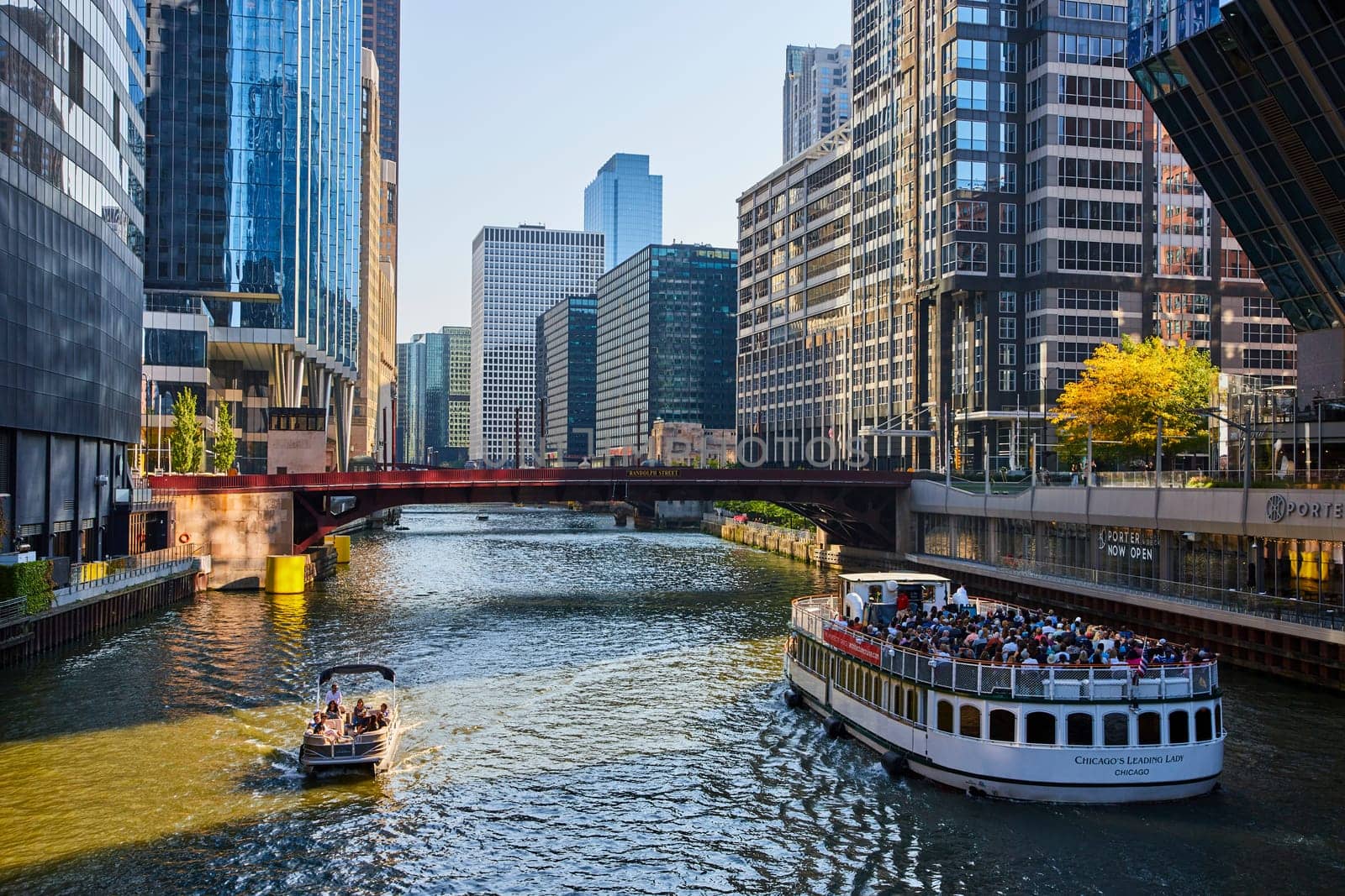Image of Tourists on white boat beside smaller vessel on Chicago canal waterway with skyscrapers, summer day