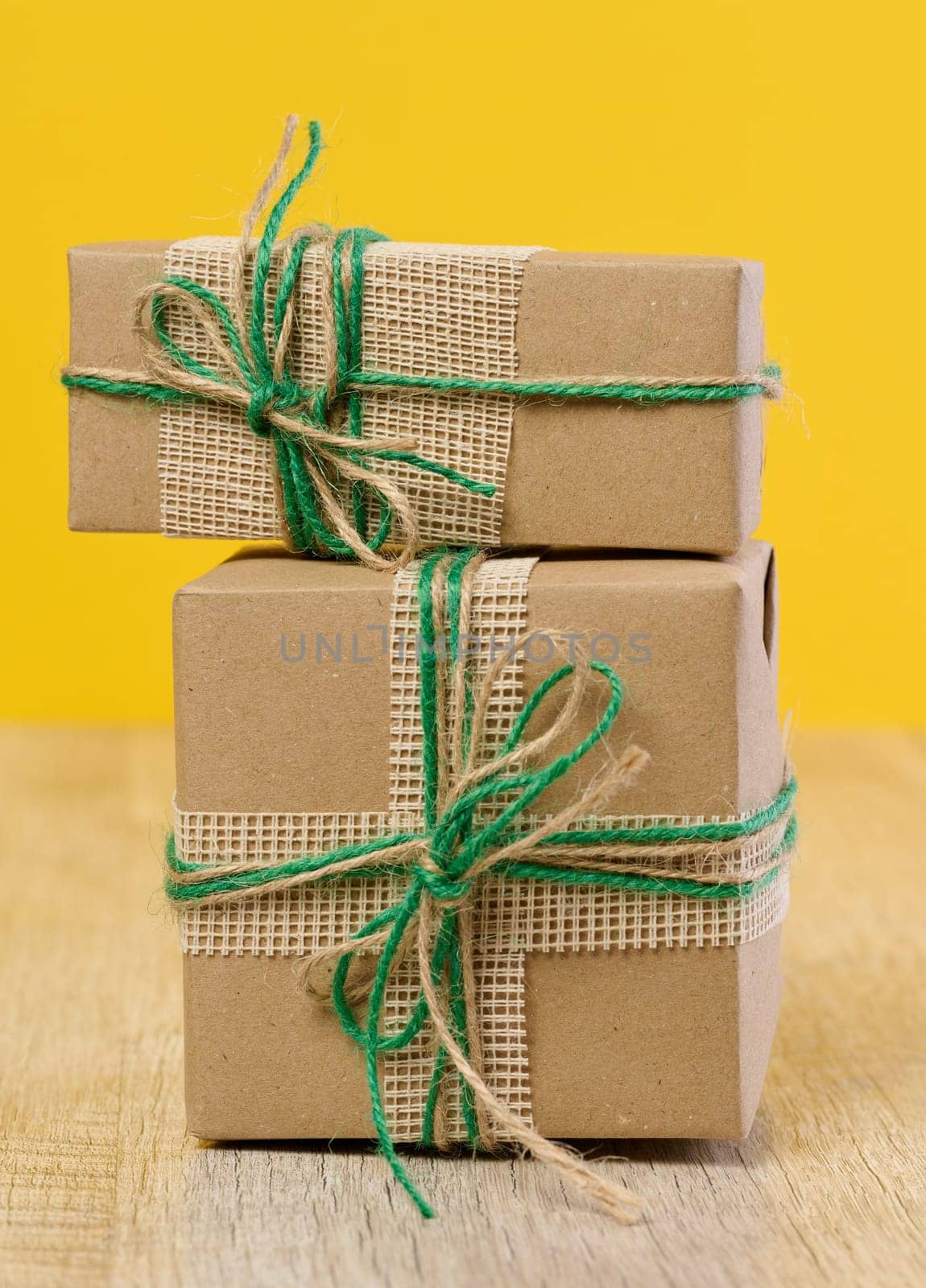 The box is packed in brown craft paper and tied with a rope on a beige background, gift