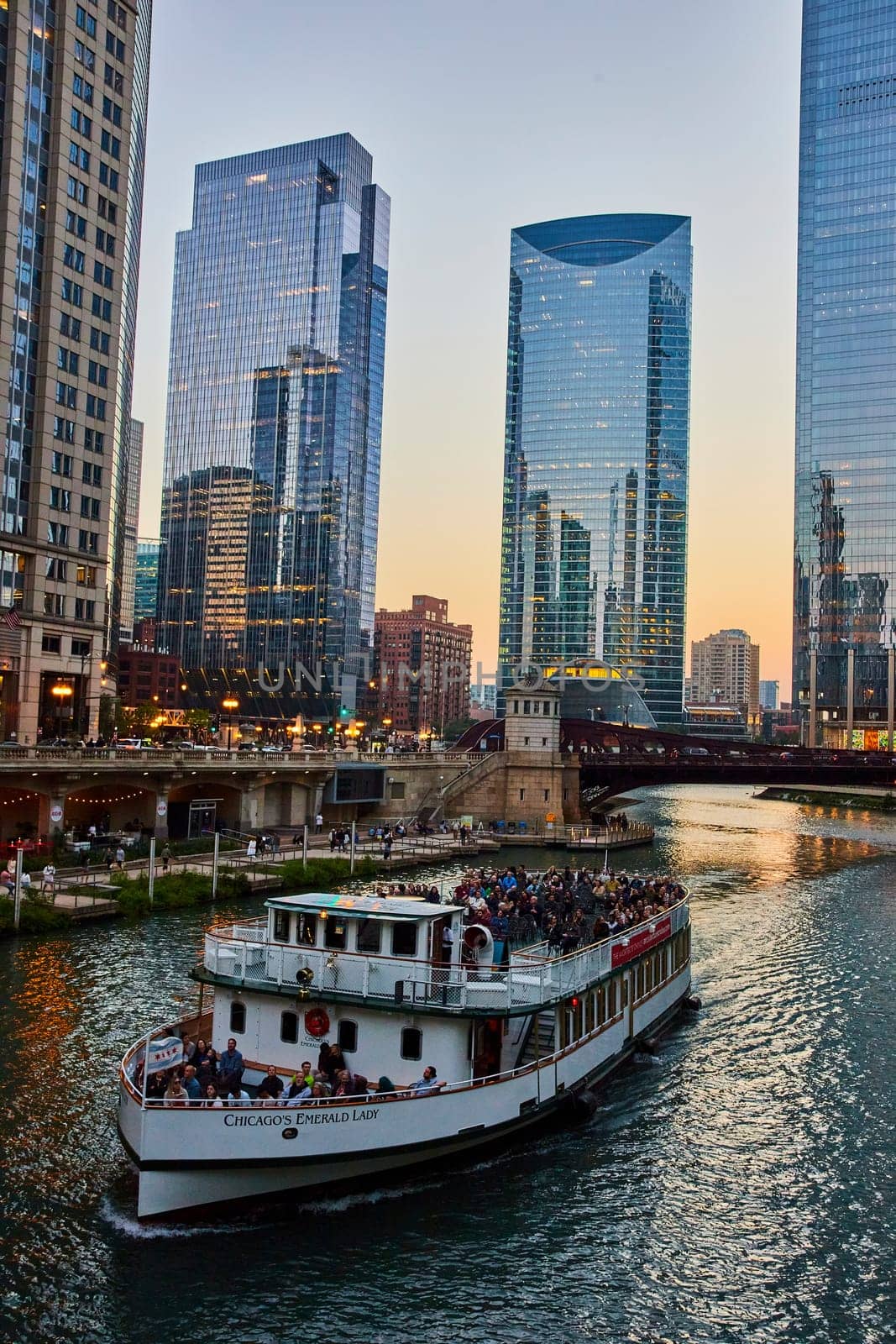 Image of Tour boat with tourists on Chicago canal with reflective dawn light on skyscrapers, IL, USA tourism