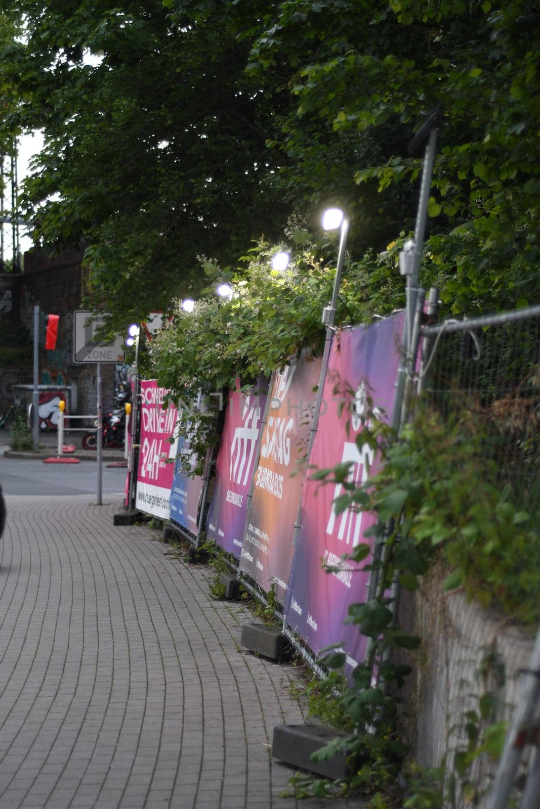 Vertical shot of a fence with posters and lighting above the billboard in Bochum, Germany