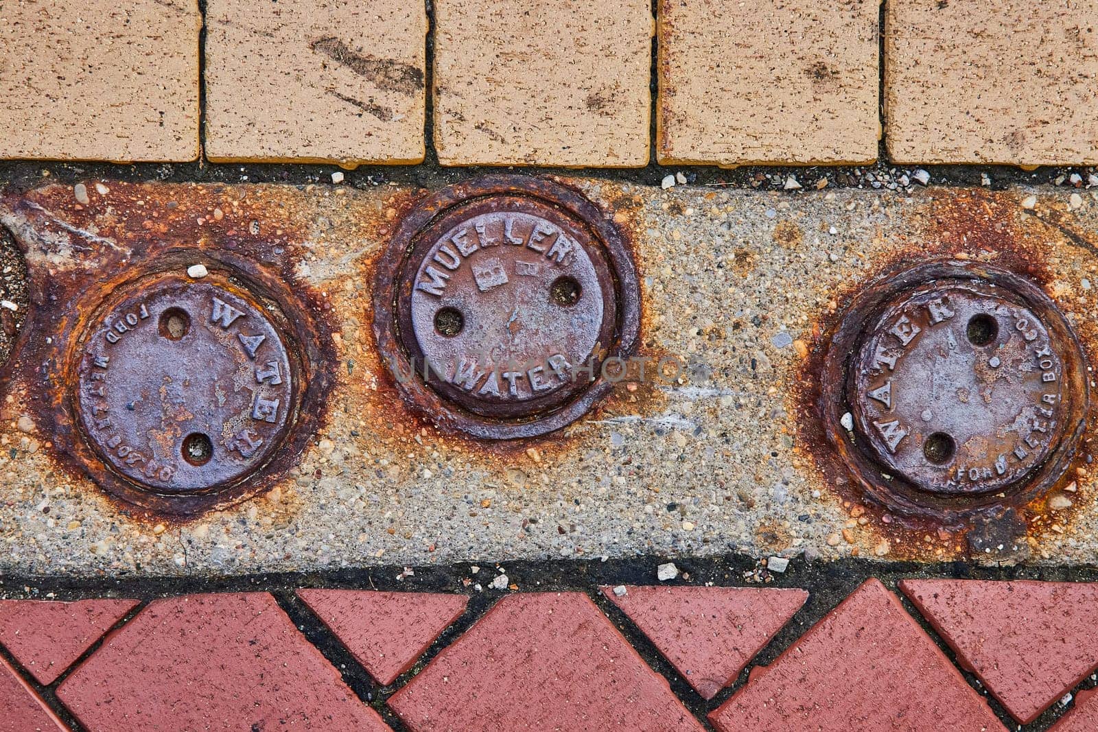 Rusty Water Utility Covers on Textured Urban Pavement by njproductions
