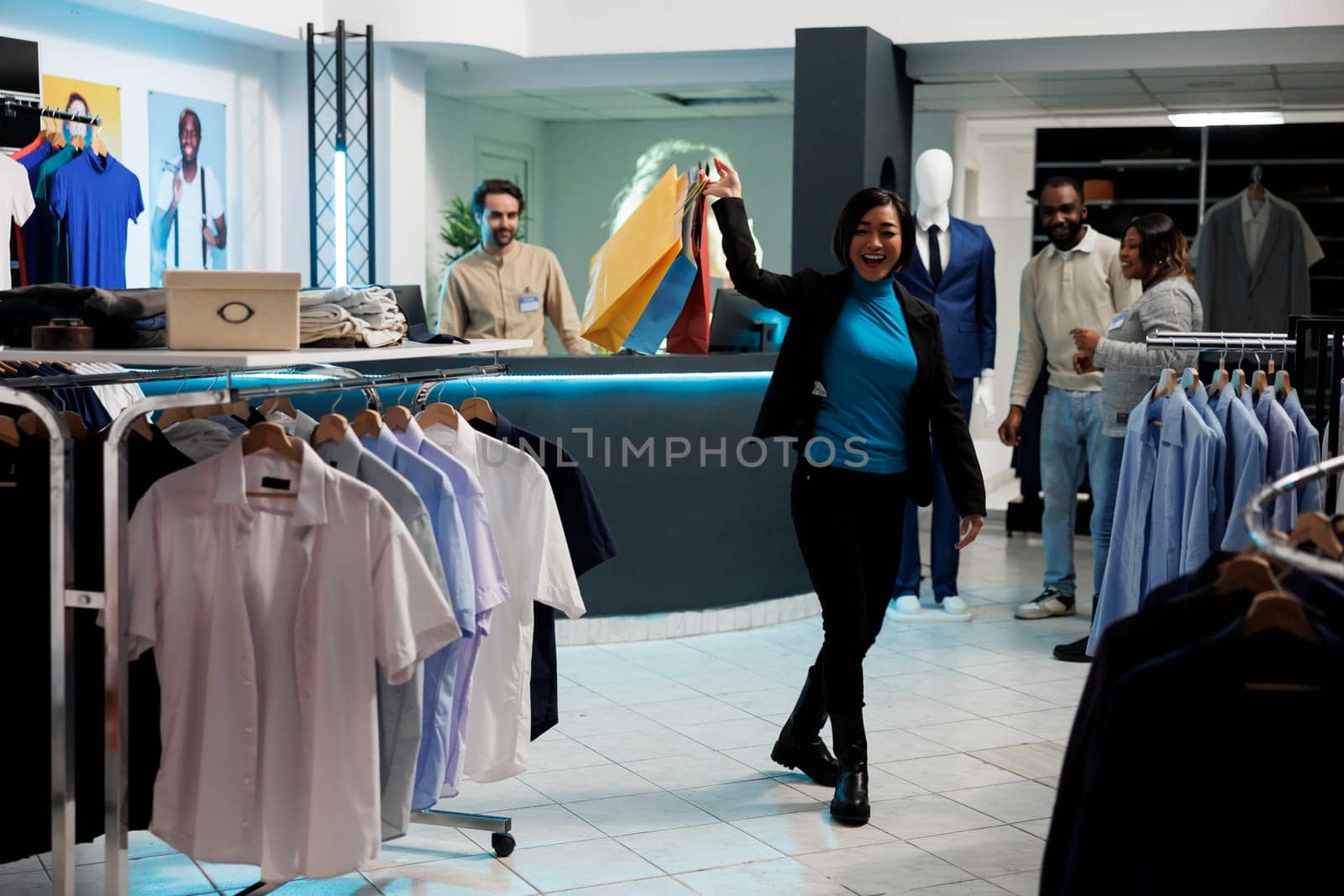 Happy asian woman laughing, holding shopping bags with purchased apparel in clothing store. Department mall satisfied cheerful customer walking with paper packages in boutique