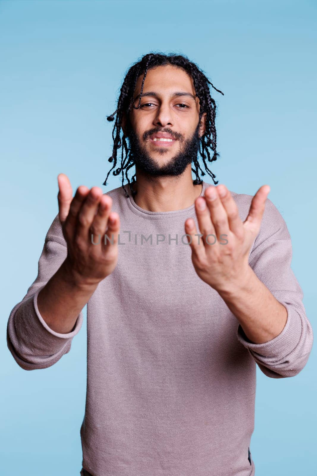 Young arab man sending air kiss with cute smile while looking at camera with charming face expression. Flirty handsome model making romantic gesture and showing love portrait