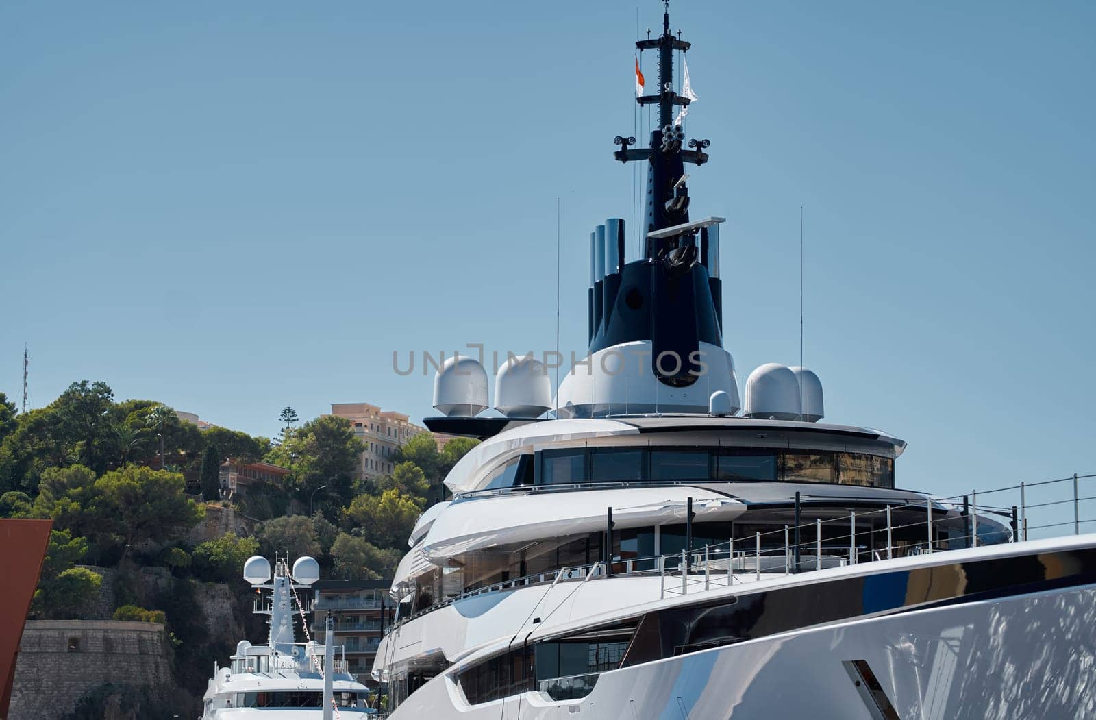 Few huge luxury yachts at the famous motorboat exhibition in the principality of Monaco, Monte Carlo, the most expensive boats for the richest people, mountain and residential complex on background. High quality photo