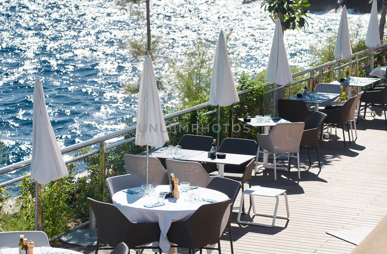 The empty cafe on embankment on the pier in the port of Monaco, water reflections on the background at sunny day. High quality photo