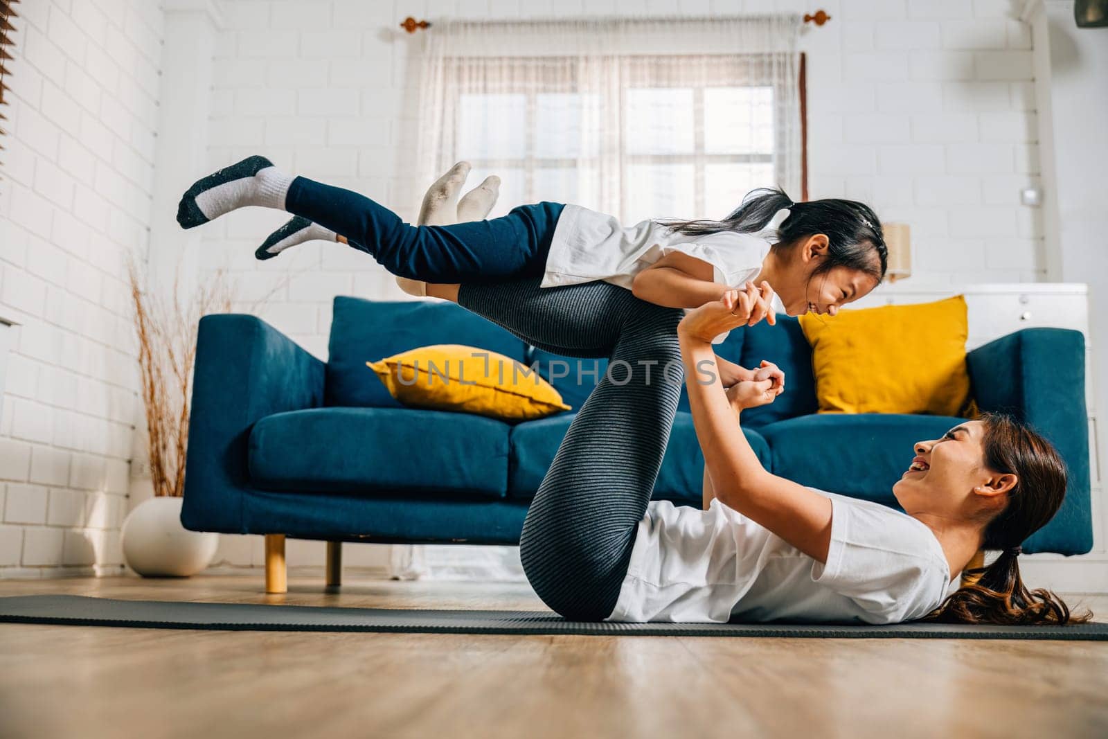 A harmonious family practices the little bird posture in yoga at home by Sorapop