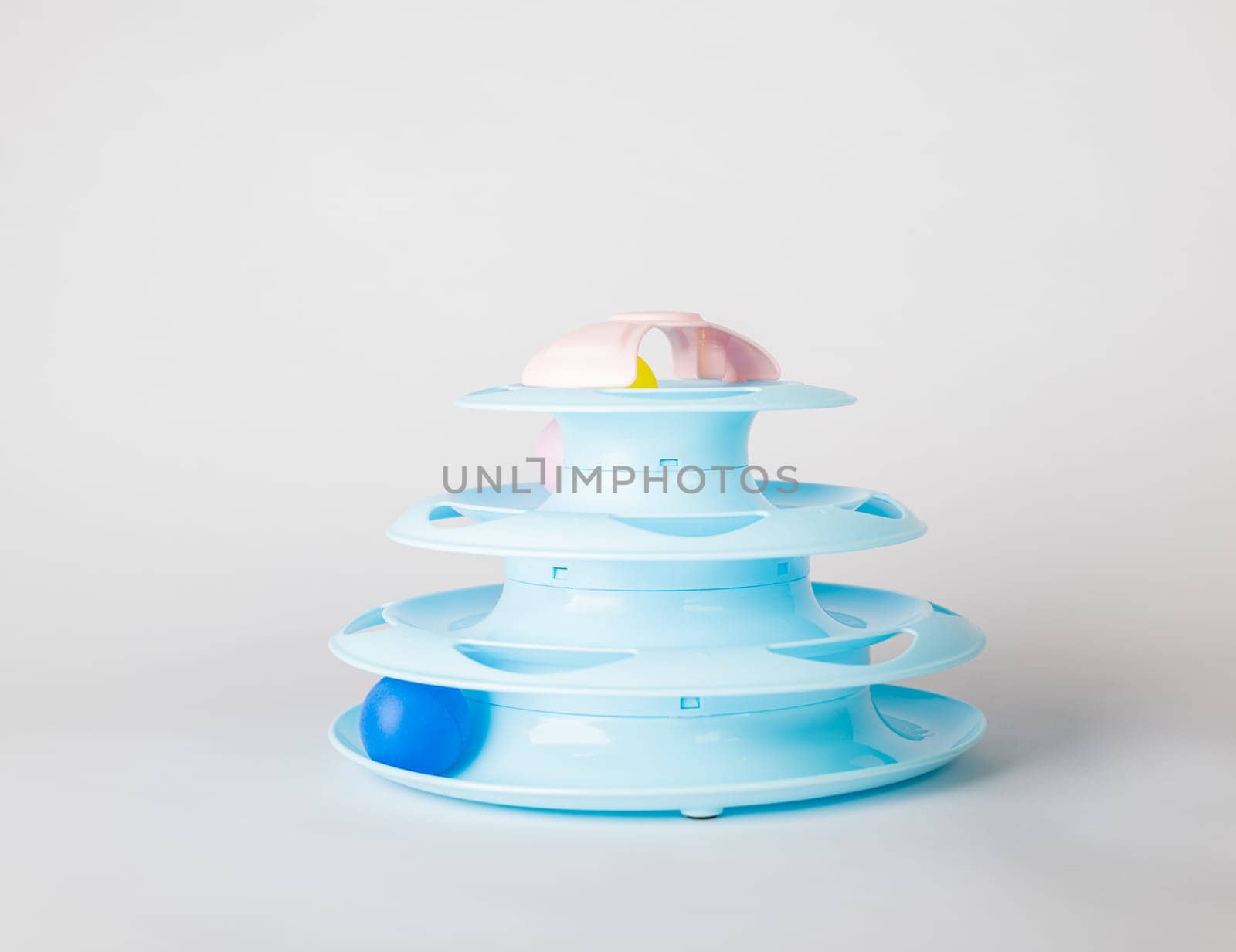 Cat's playtime showcased, a blue tower toy with a circular turntable and a moving ball, isolated on white. Witness feline intelligence and hunter instincts as the paw grips for fun. by Sorapop