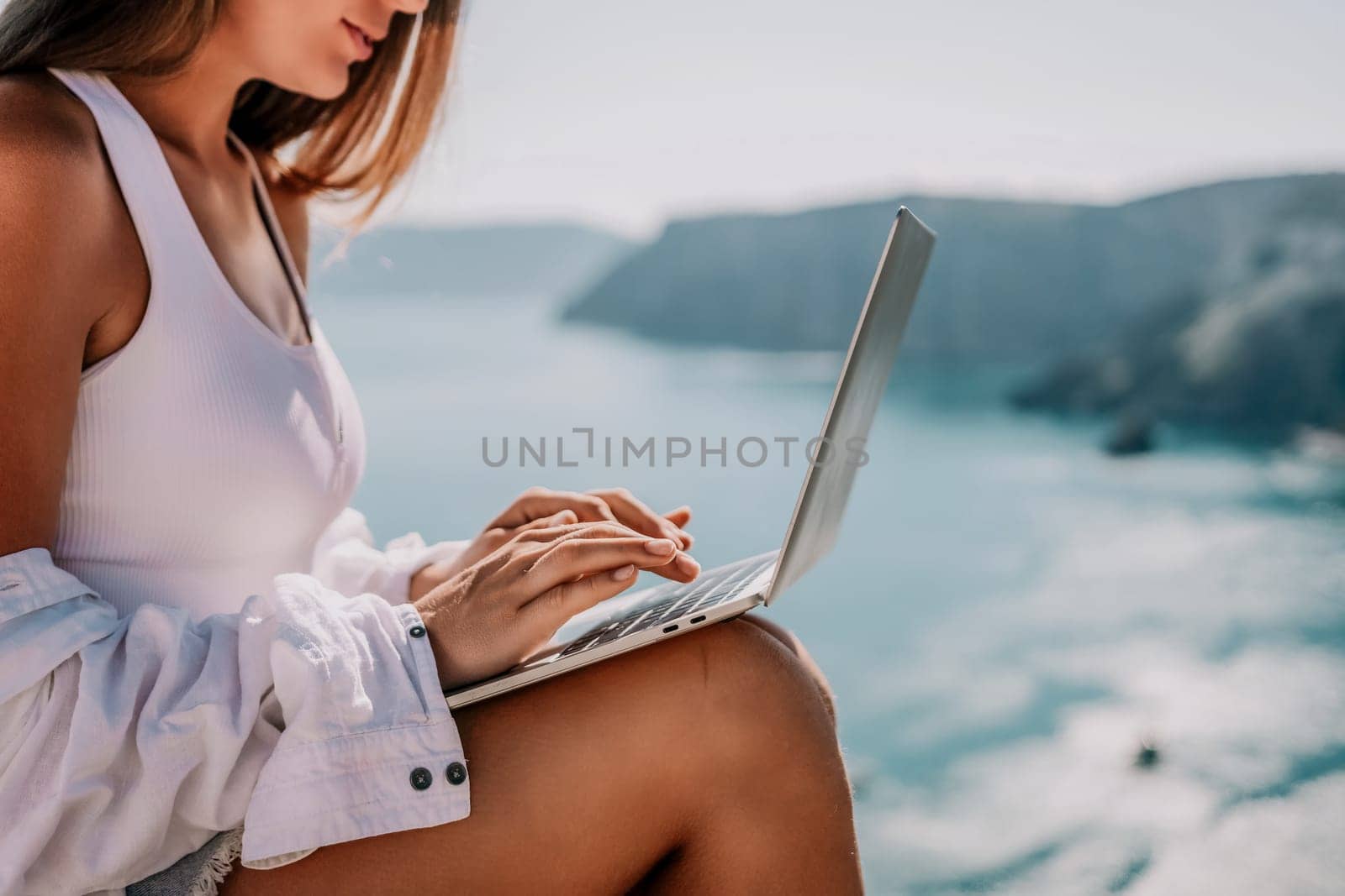 Woman sea laptop. Business woman in yellow hat freelancer with laptop working over blue sea beach. Girl relieves stress from work. Freelance, digital nomad, travel and holidays concept by panophotograph