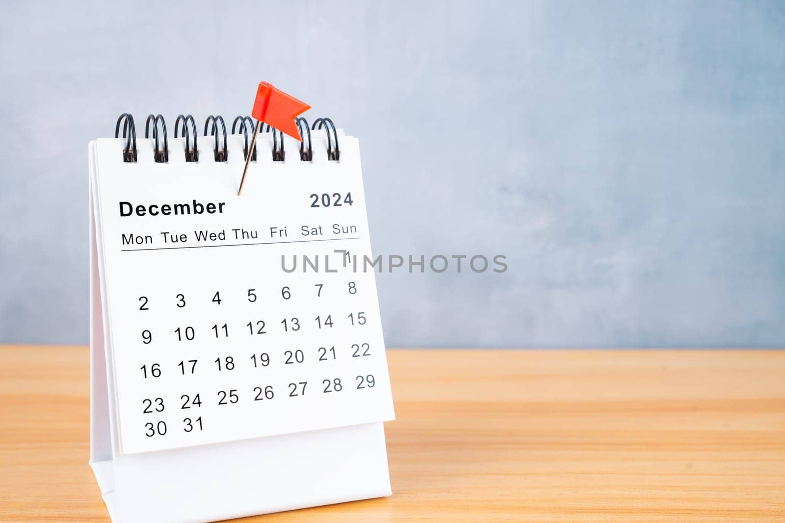 December 2024 calendar and red push pin on wooden table.