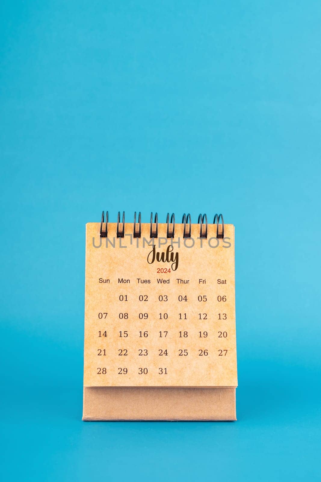 July 2024 white desk calendar on blue background. by Gamjai
