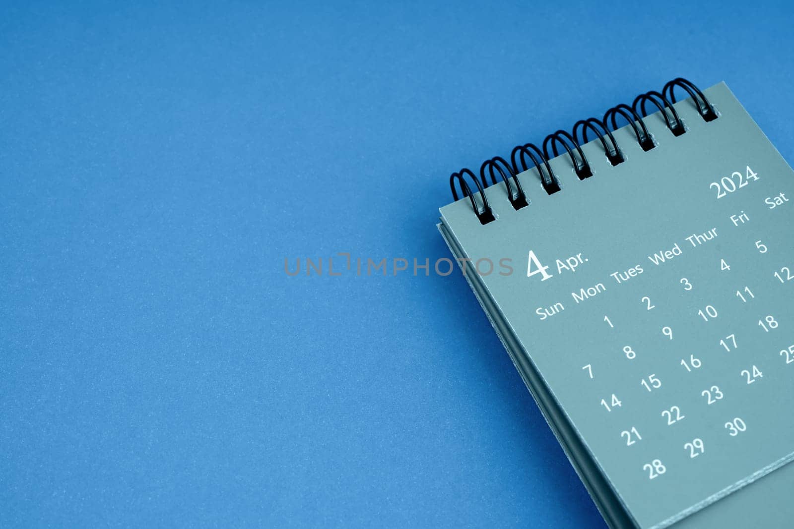 April 2024 desk calendar on blue color background. by Gamjai