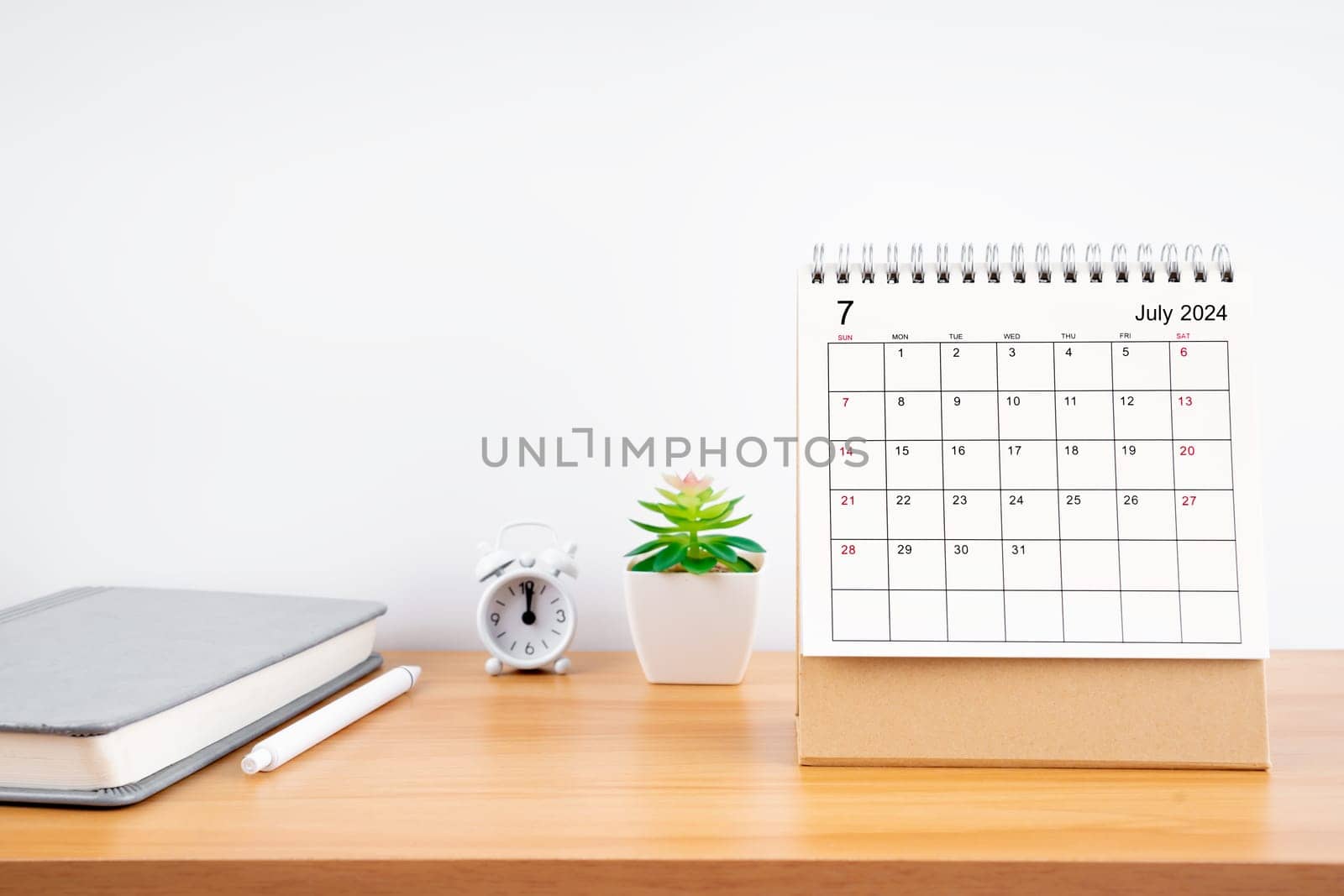 July 2024, Monthly desk calendar for 2024 year on wooden table with diary.