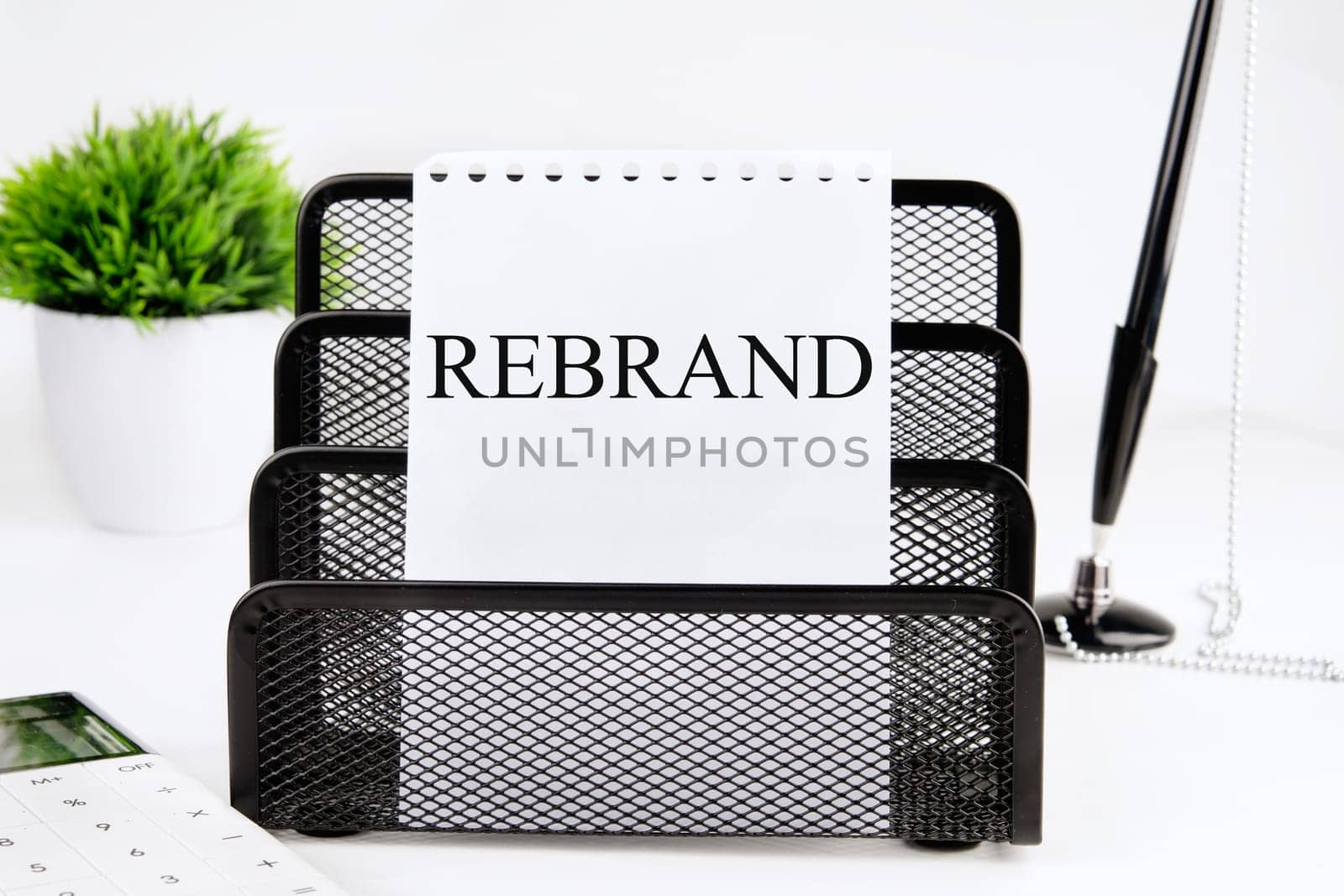 REBRAND A word written on a piece of paper from a notebook on a stand on a white background