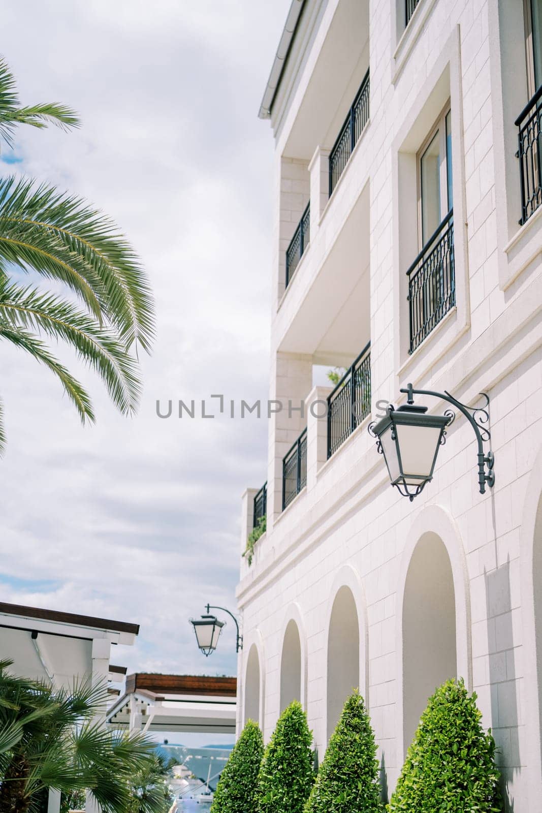 Lanterns hang on the facade of a modern hotel with large terraces by Nadtochiy