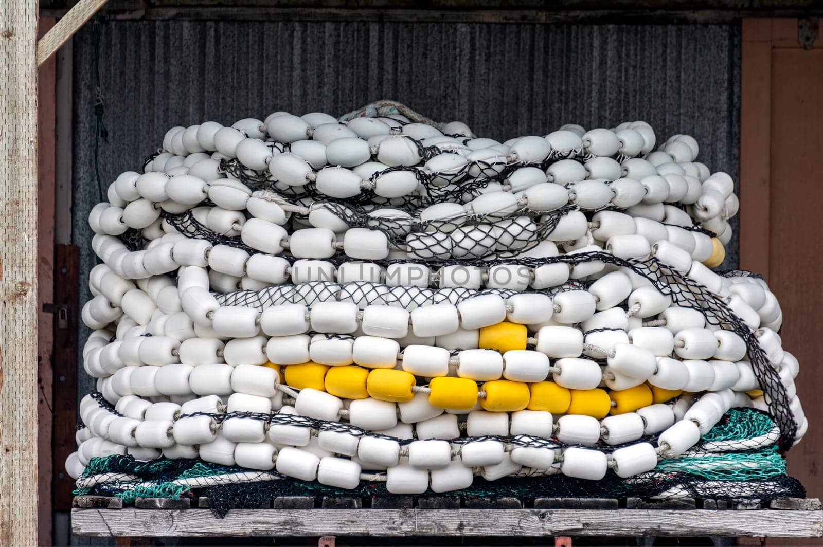 Trawler fishing net and floats stored on wooden pallet under a shed