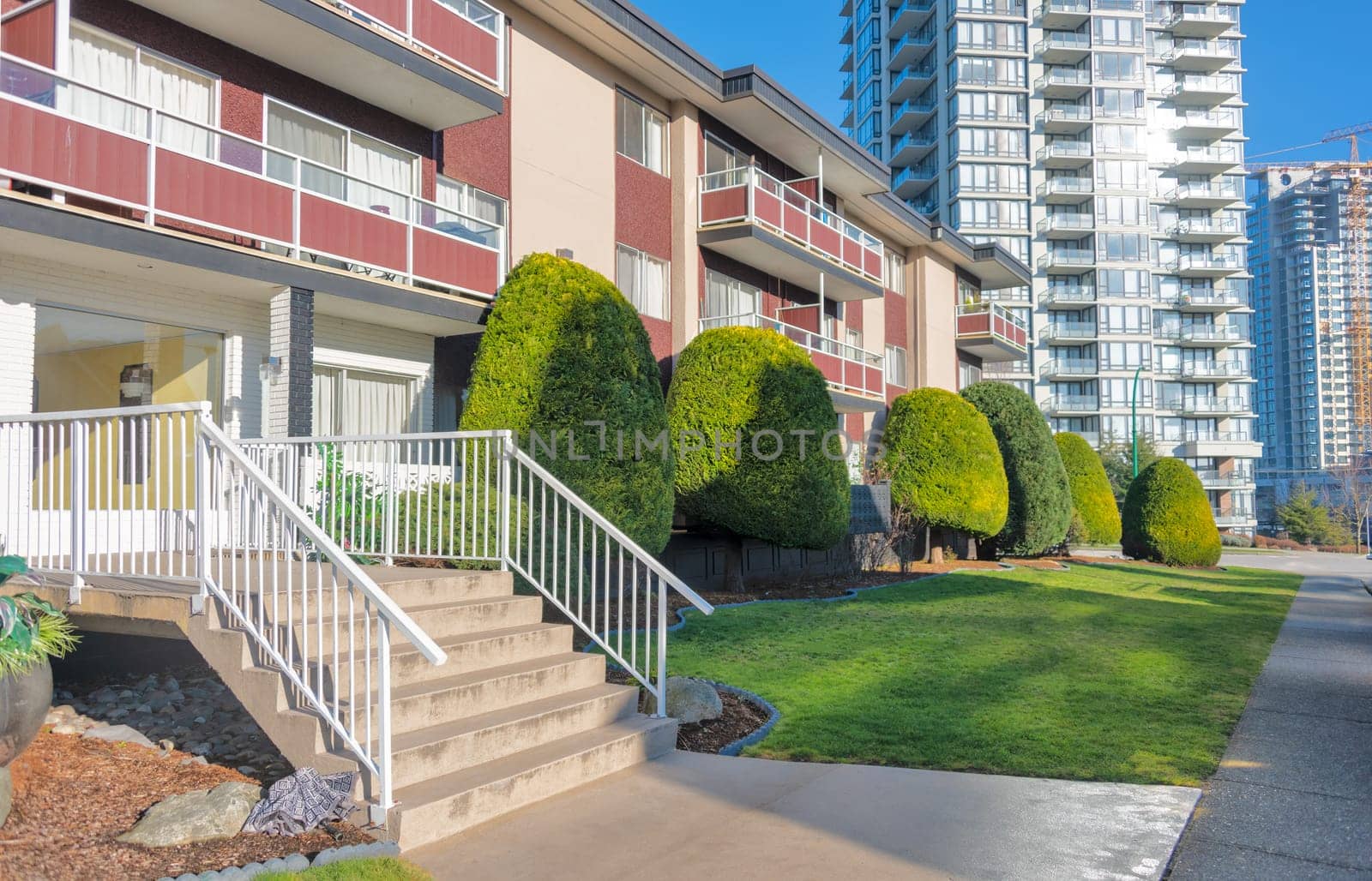 Small porch with steps to the entrance at low rise residential building on the high rise background