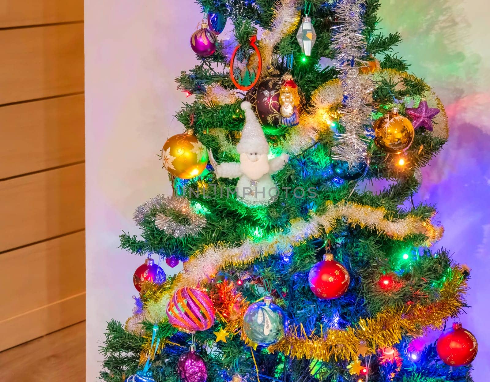 Decorated Christmas tree on white wall background in the corner of the room.