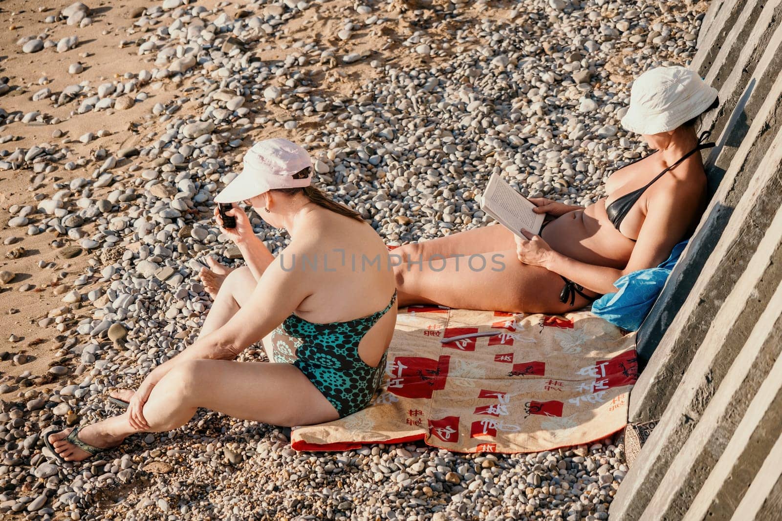 Woman reading book and Sitting on the Beach on Vacation. Summer Holidays Travel Concept. Summer chill. Rest and pleasure. Holidays on the beach. Side view by panophotograph