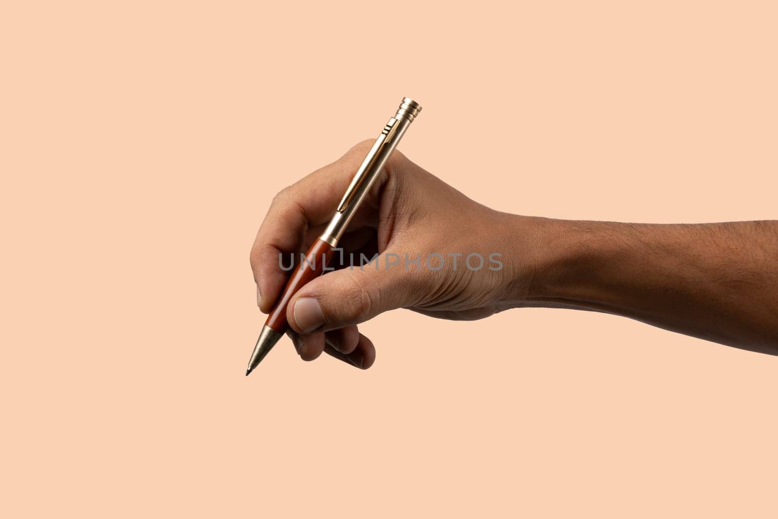 Closeup of male hand holding pen and writing or signing isolated on salmon by TropicalNinjaStudio