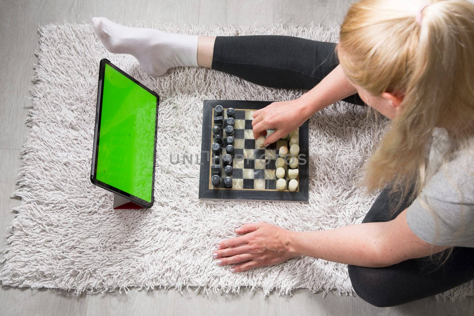 woman playing chess on the carpet with a virtual partner on a tablet, green screen tablet, mockup for app advertising by KaterinaDalemans