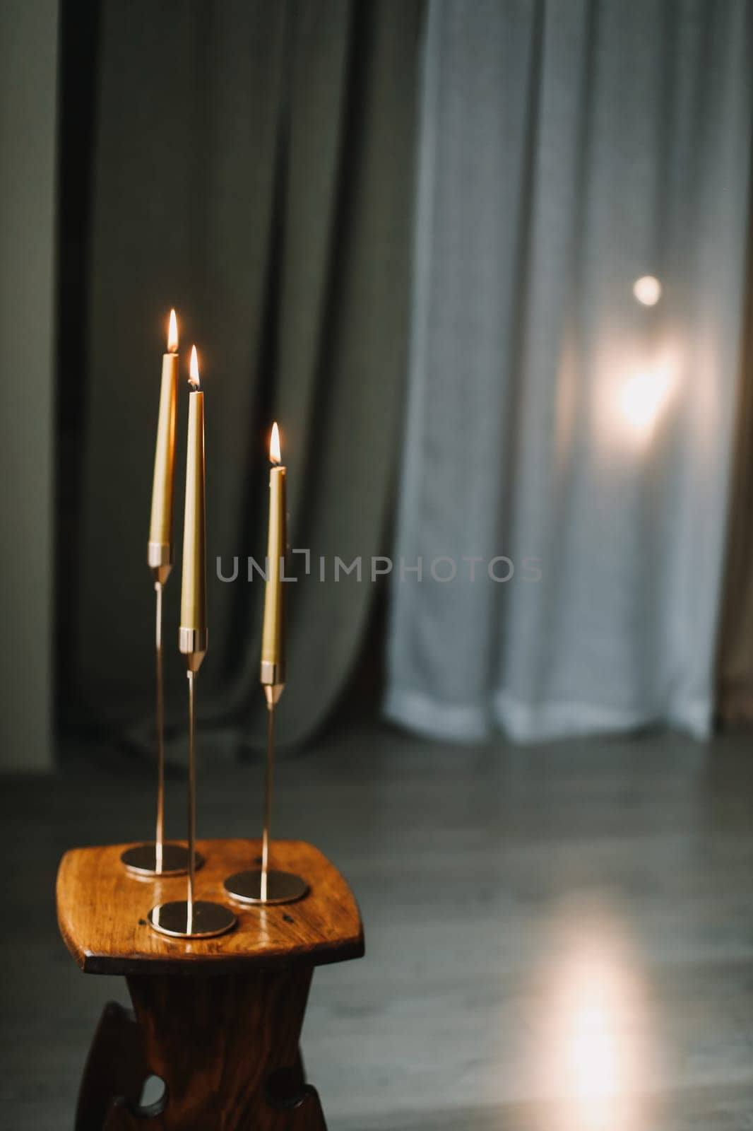 Golden color painted long candles on wooden table at home. Modern living room interior composition with Christmas decorations. New Year, Christmas wallpaper.