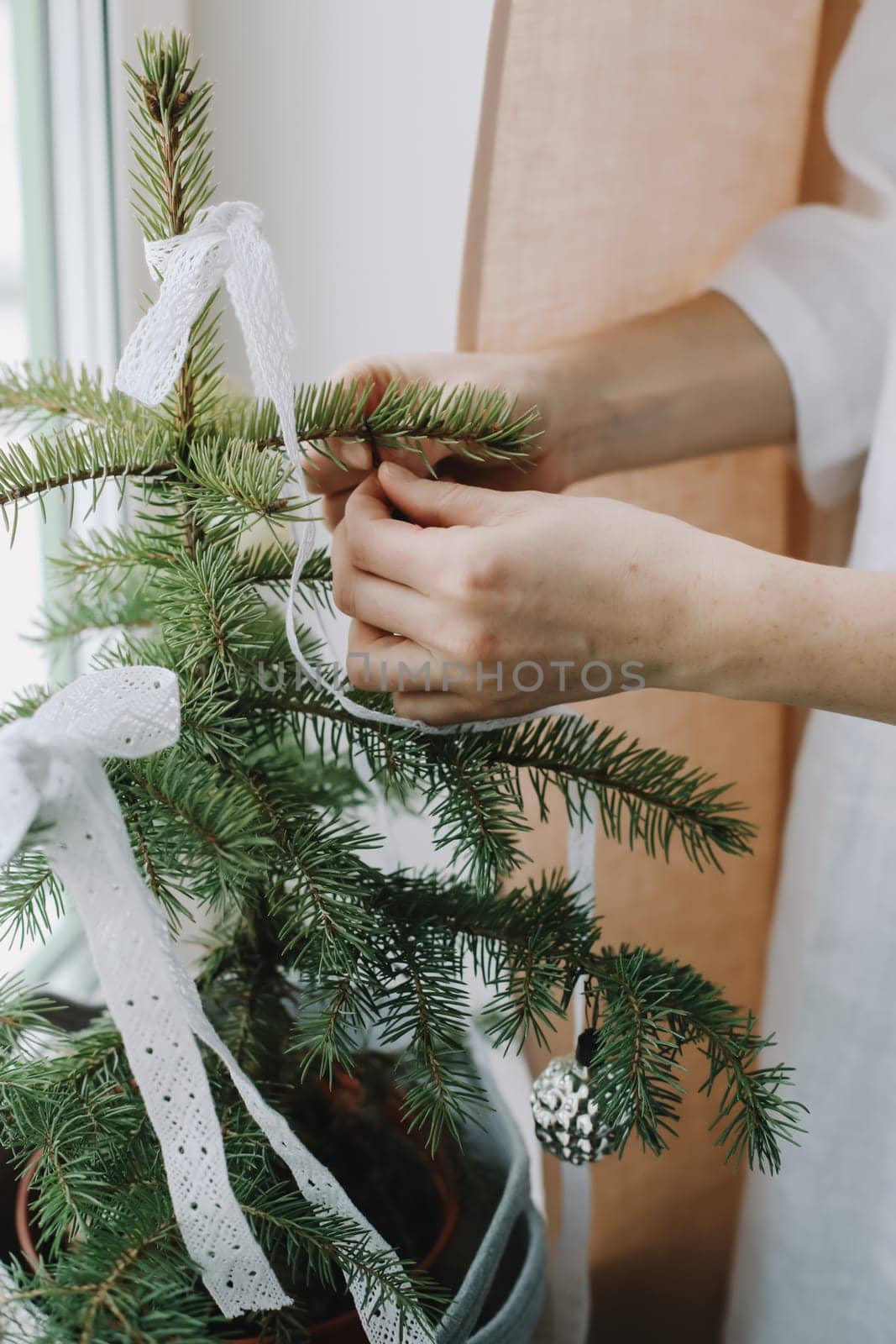 Woman hands decorating christmas tree. Atmospheric time. Holiday, Christmas and New Year family celebration concept. by paralisart