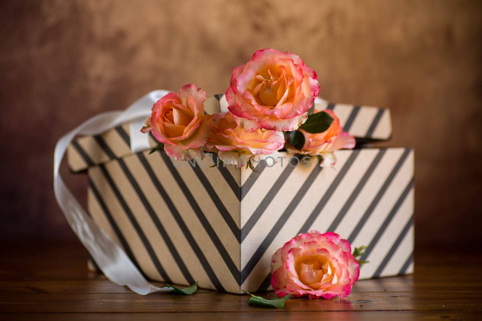 gift box with ribbons and beautiful roses inside, on a wooden table.