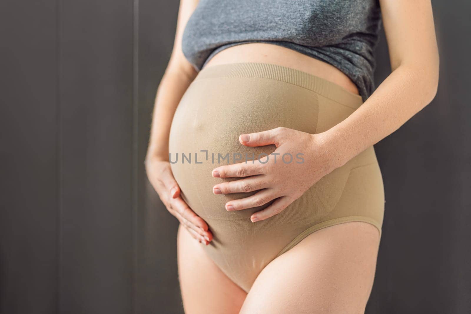 Pregnant bliss: Mom-to-be embraces her baby bump with a soft fabric bandage, providing gentle support. Maternity made comfortable.