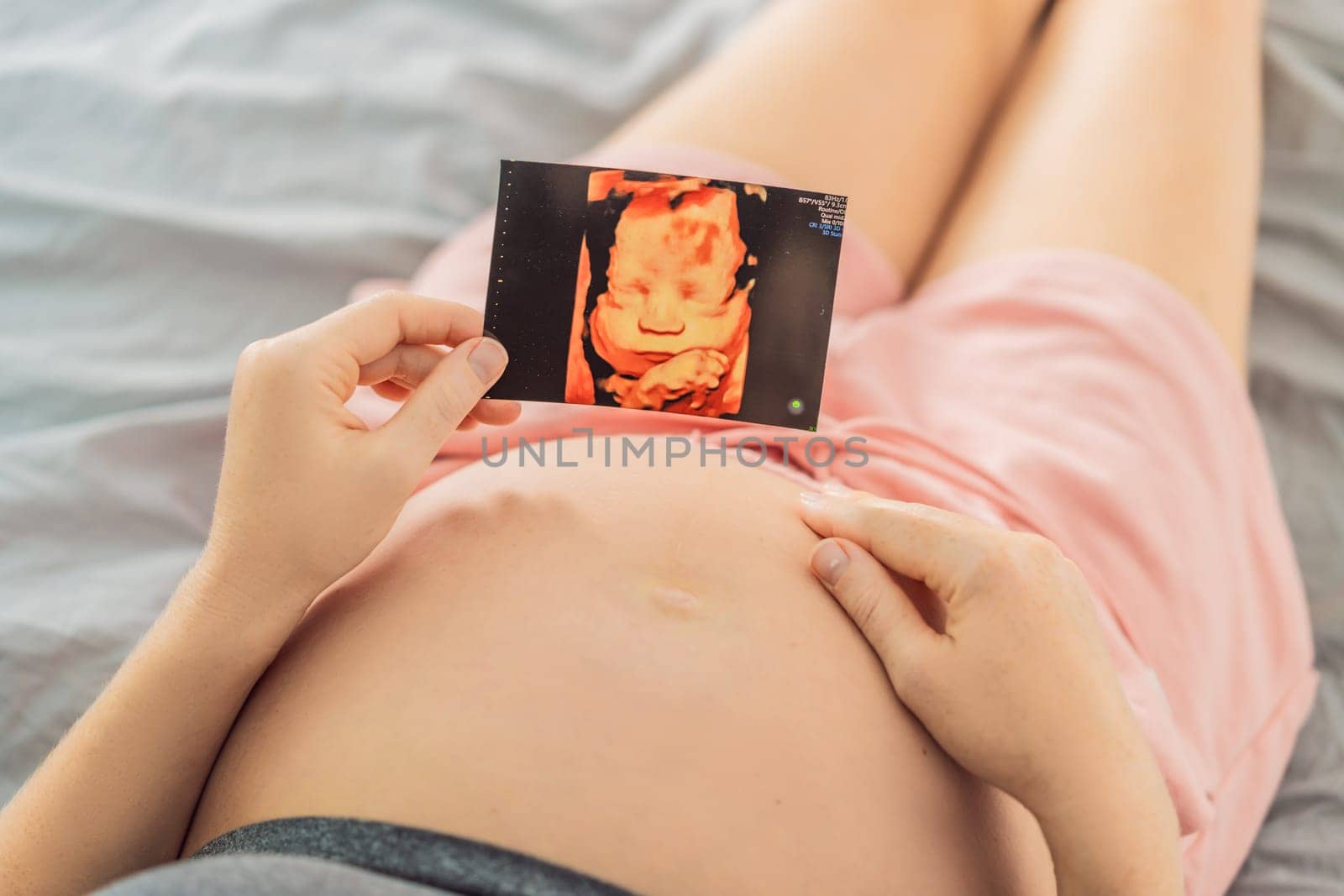 Expectant mother tenderly connects with her unborn child, holding ultrasound photo to her pregnant belly.