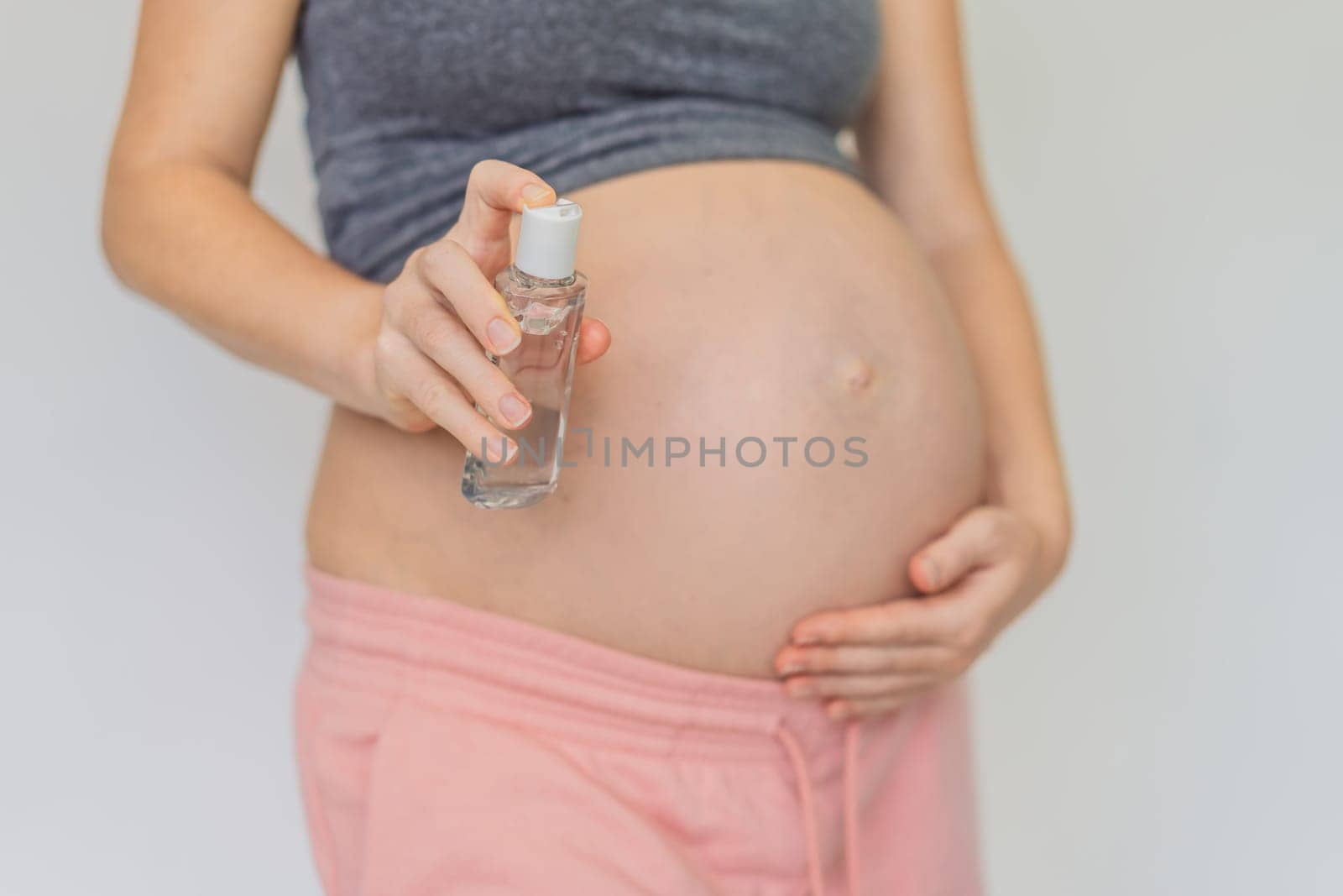 Expectant mom ensures safety, applying gel sanitizer for a clean and healthy pregnancy.