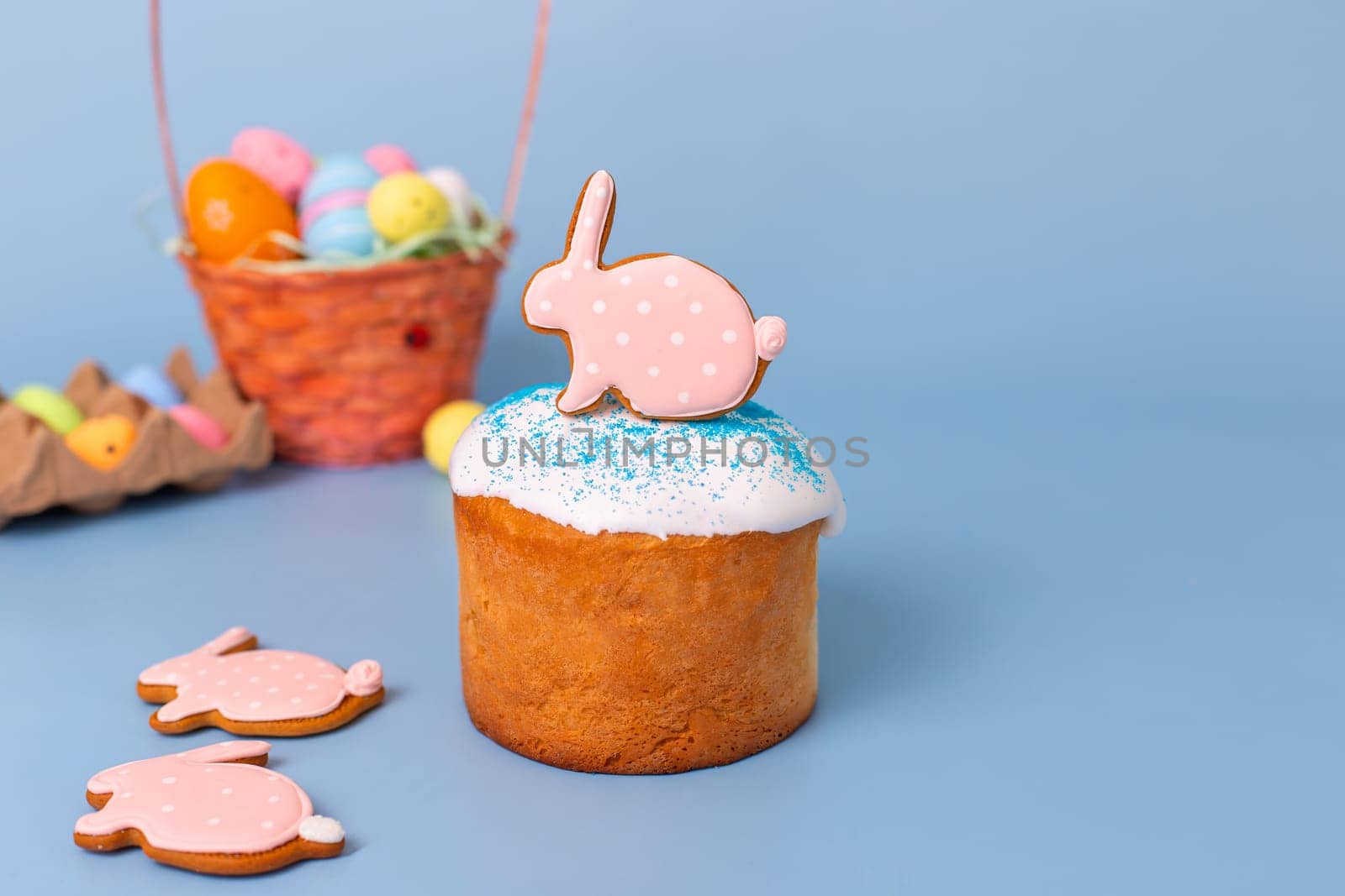Tasty pink gingerbread in the form of a rabbit on Easter cake stand on a blue background.