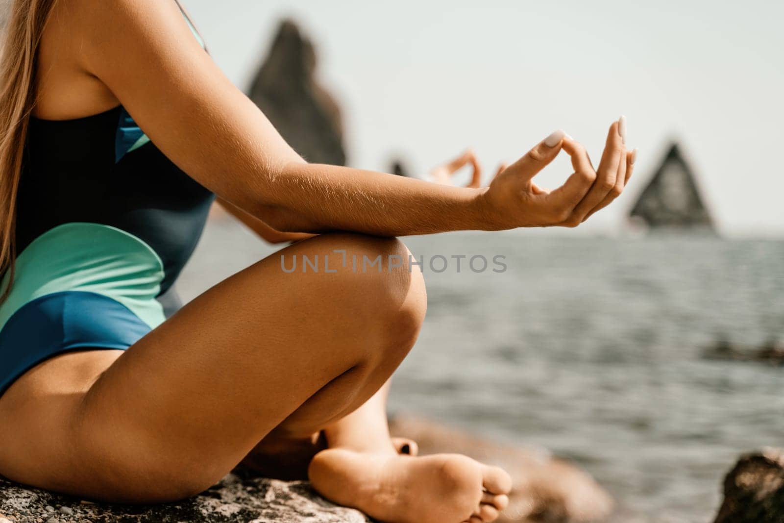 Yoga on the beach. A happy woman meditating in a yoga pose on the beach, surrounded by the ocean and rock mountains, promoting a healthy lifestyle outdoors in nature, and inspiring fitness concept. by Matiunina