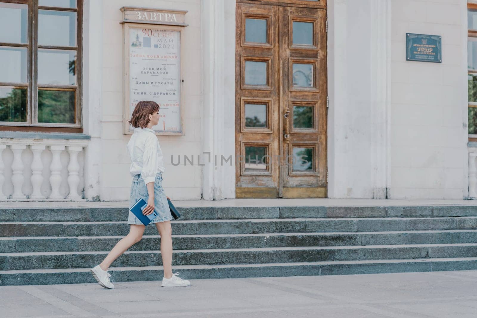 Woman staircase city. A business woman in a white shirt and denim skirt walks down the steps of an ancient building in the city by Matiunina